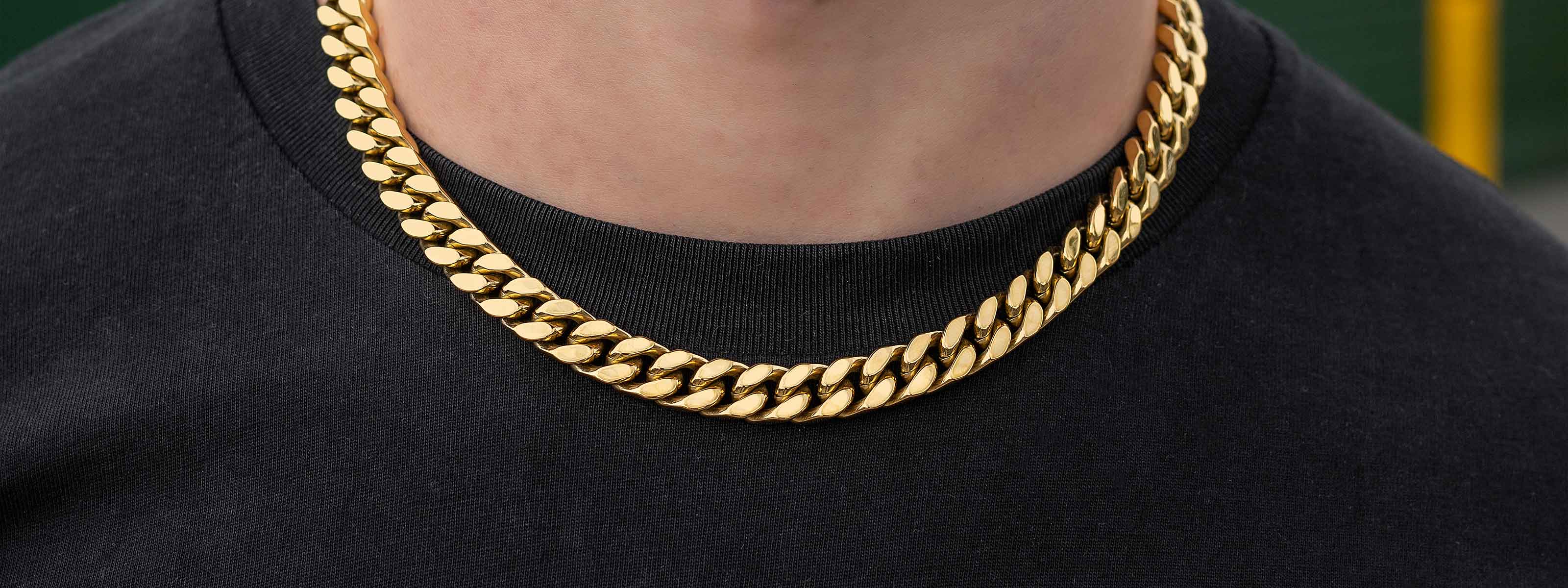 Close-up of a person wearing a thick gold chain necklace over a black t-shirt, with only the lower part of their face and neck visible.