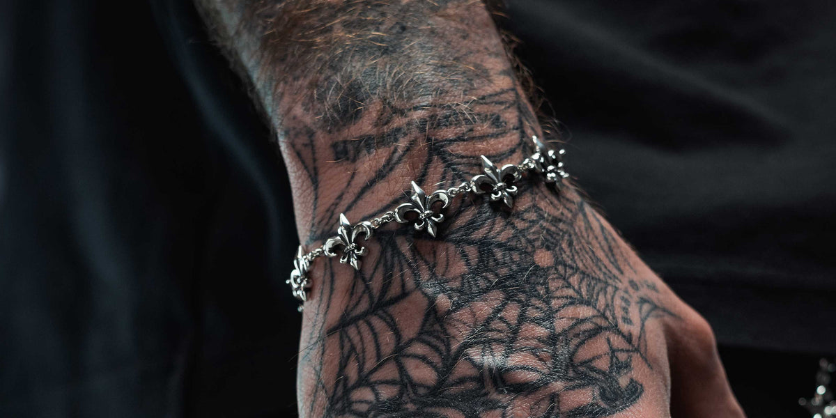 A close-up of various silver chains and bracelets displayed on a black velvet stand, showcasing different link styles and textures against a dark background.