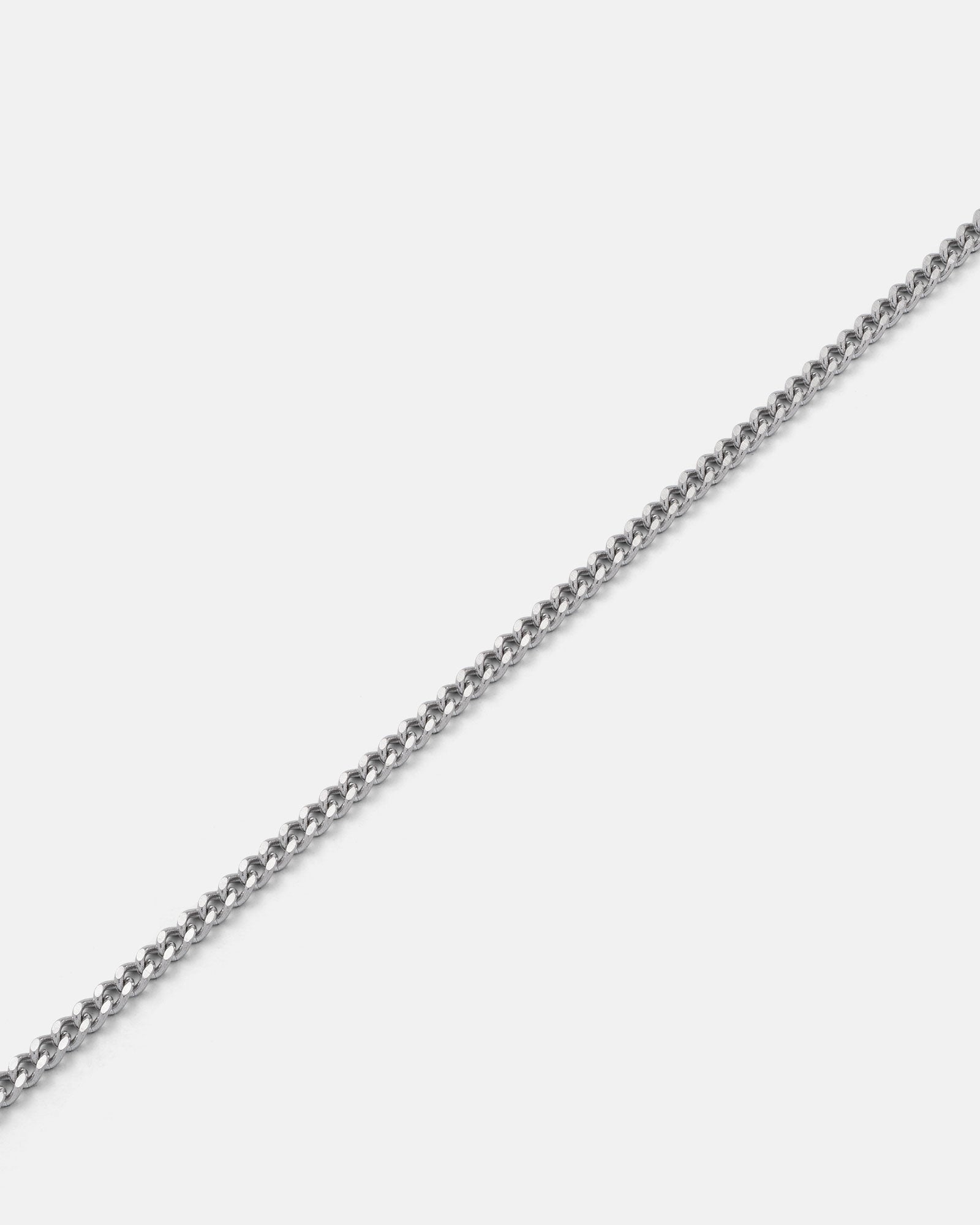 A close-up of the 2.3mm Curb Chain, a thin silver necklace, diagonally displayed on a plain white background.