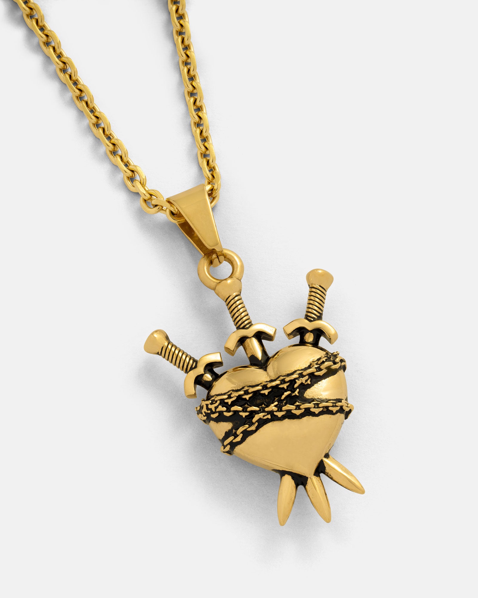 The "3 of Swords" Pendant (Gold) is an 18k gold-plated heart-shaped necklace, pierced by three swords and wrapped in barbed wire, inspired by the iconic Three of Swords card, shown against a plain light background.
