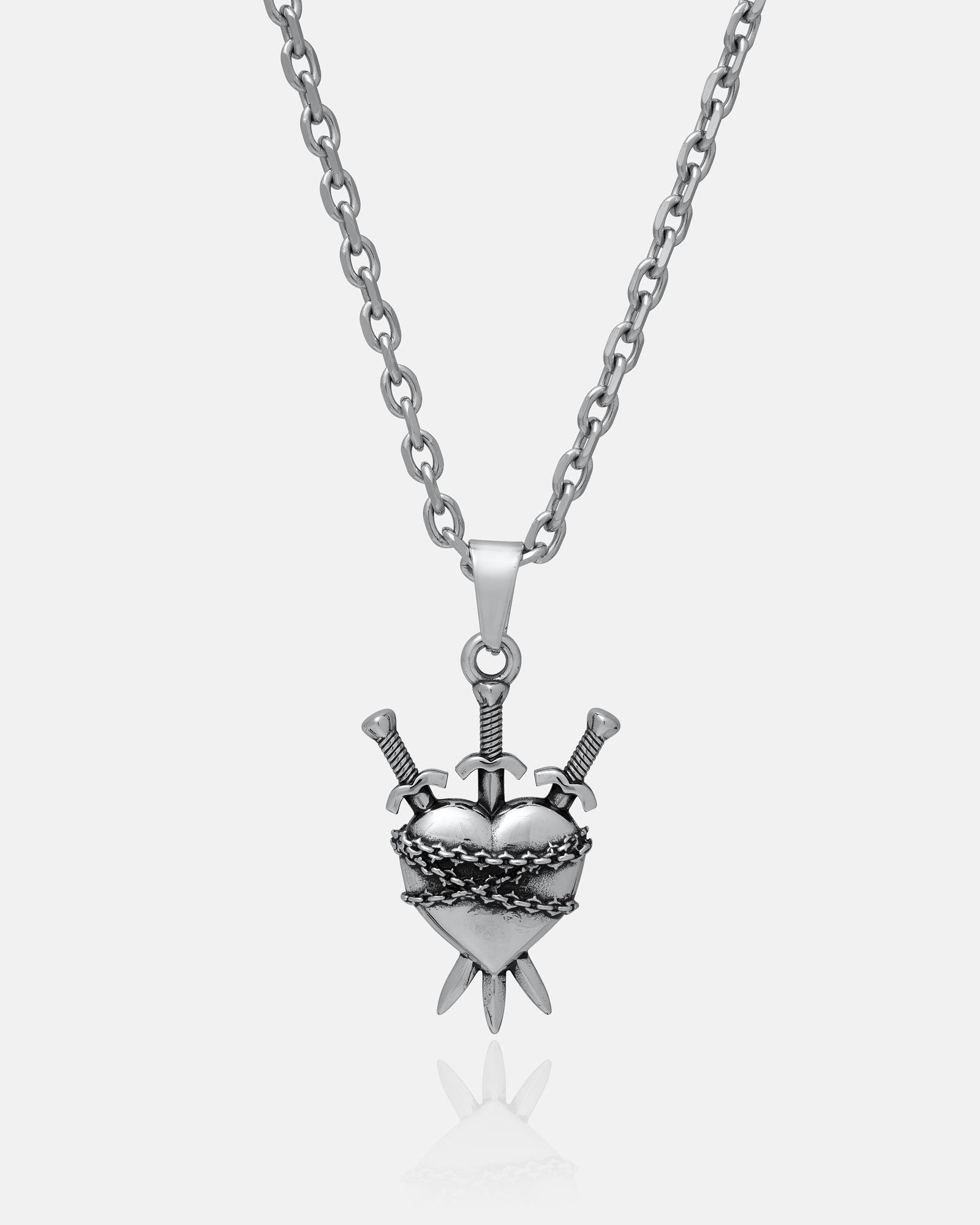 The "3 of Swords" Pendant by Statement Collective is a silver necklace featuring a heart-shaped pendant pierced by three swords and entwined in barbed wire, drawing inspiration from heartbreak symbolism and the iconic tarot jewelry design, captured against a plain white background.
