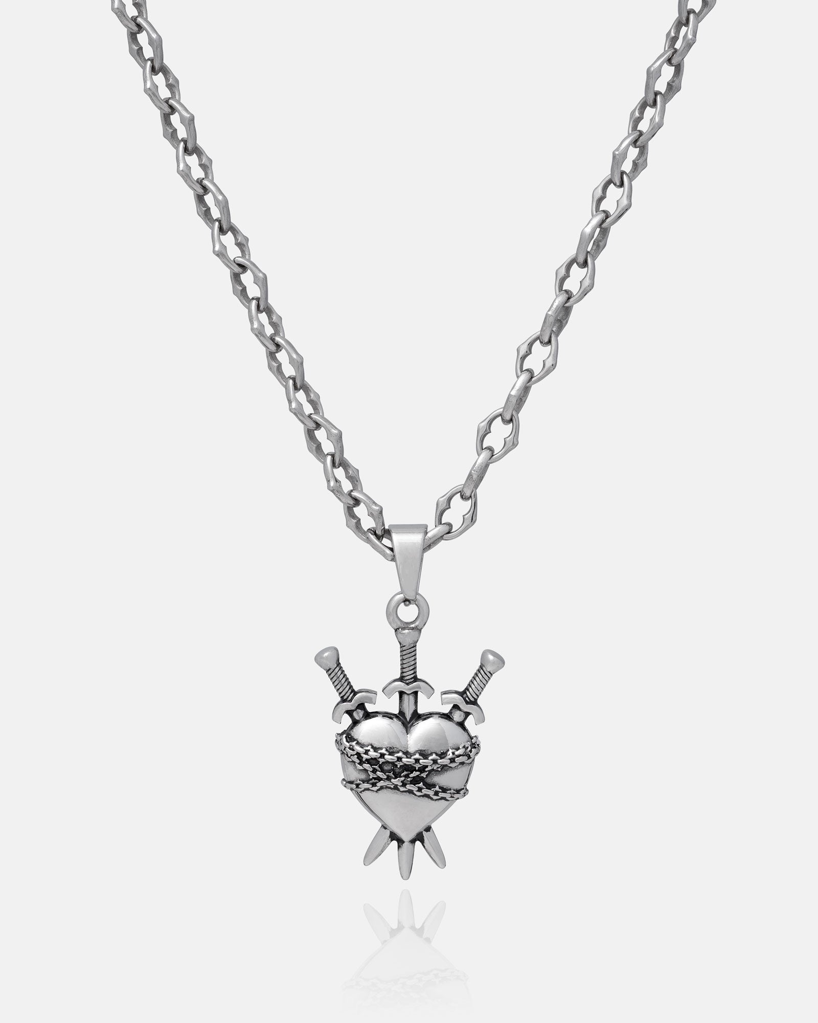 The Cathedral" 6mm spiked chain necklace features a stainless steel heart pendant pierced by three swords, with ornate detailing. The textured chain and pendant are shown against a plain white background. Custom pendant choice available.