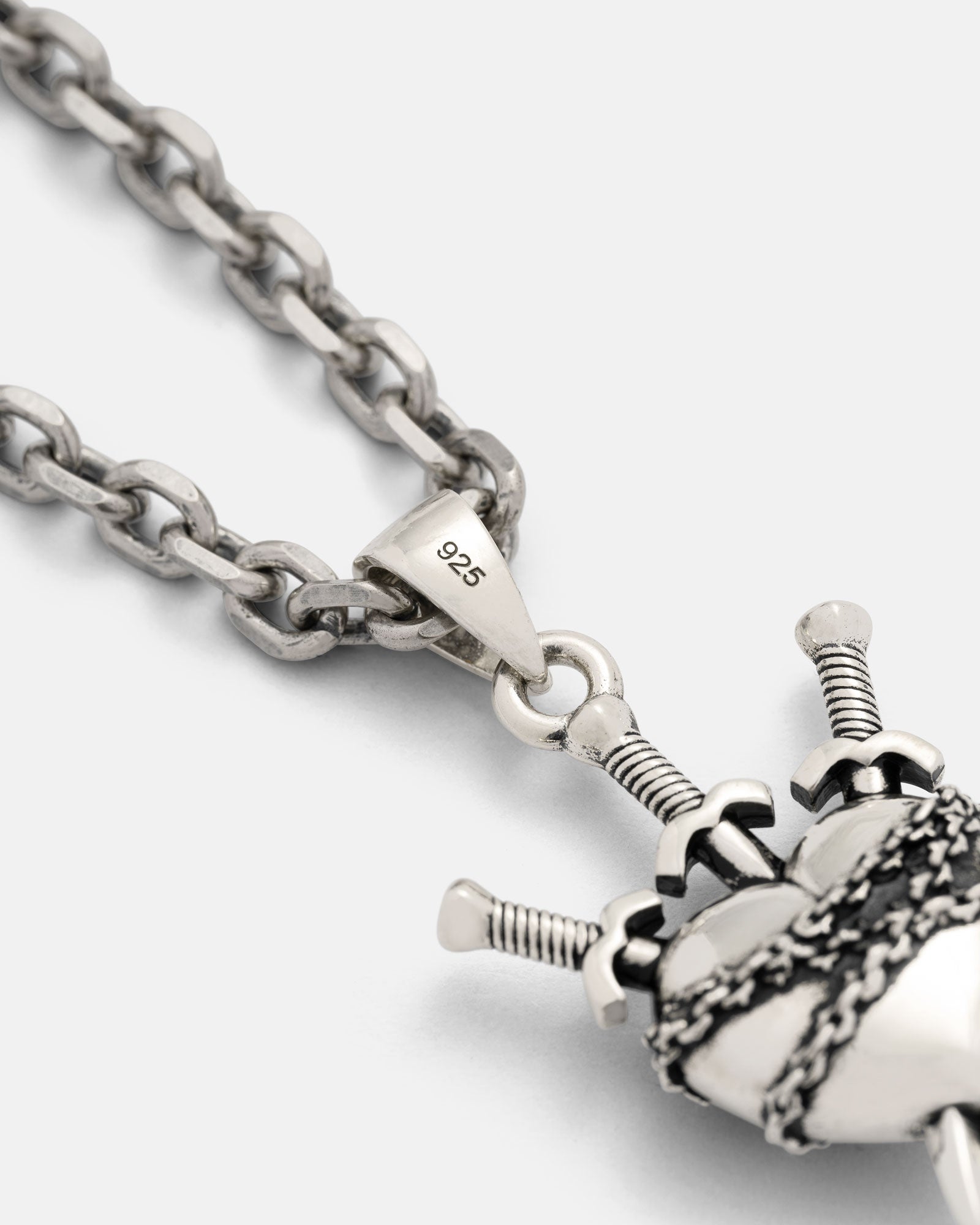 Close-up of the 925 Sterling Silver "3 of Swords" Pendant, featuring an anatomical heart pierced by three swords. The pendant and its chain are displayed on a plain light gray background.