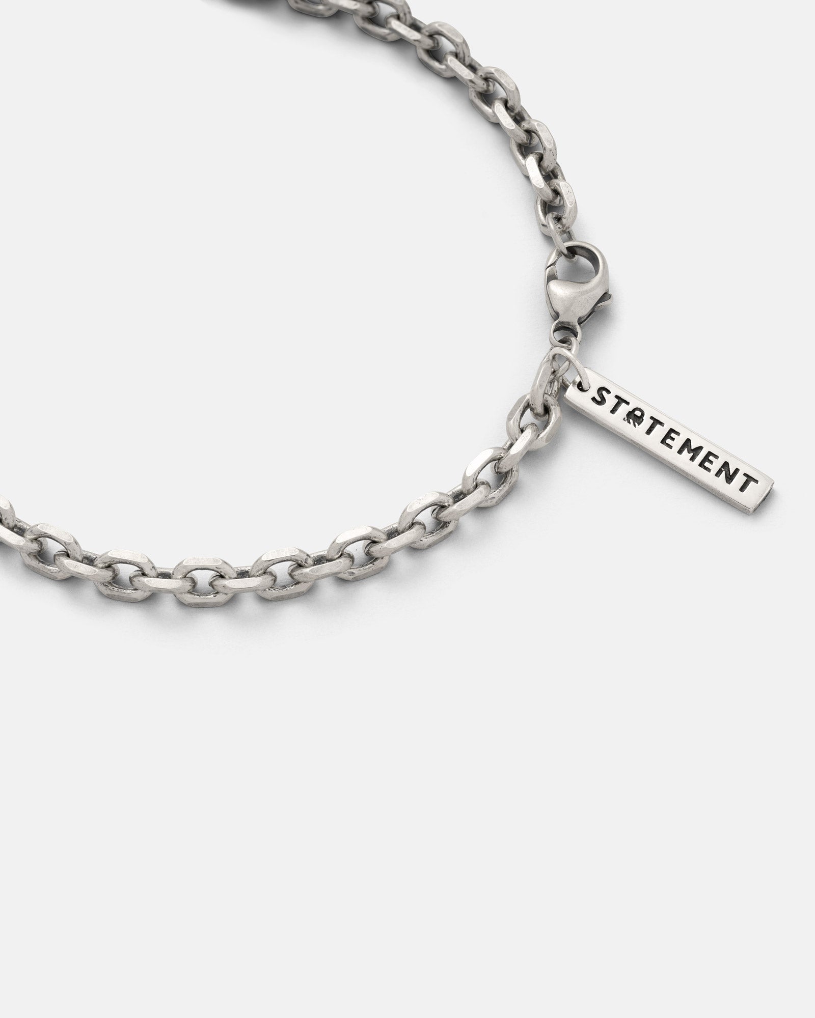 Close-up of a 925 Sterling Silver 4.5mm Cable Chain necklace with a lobster clasp and a rectangular charm engraved “STATEMENT” on a plain white background.