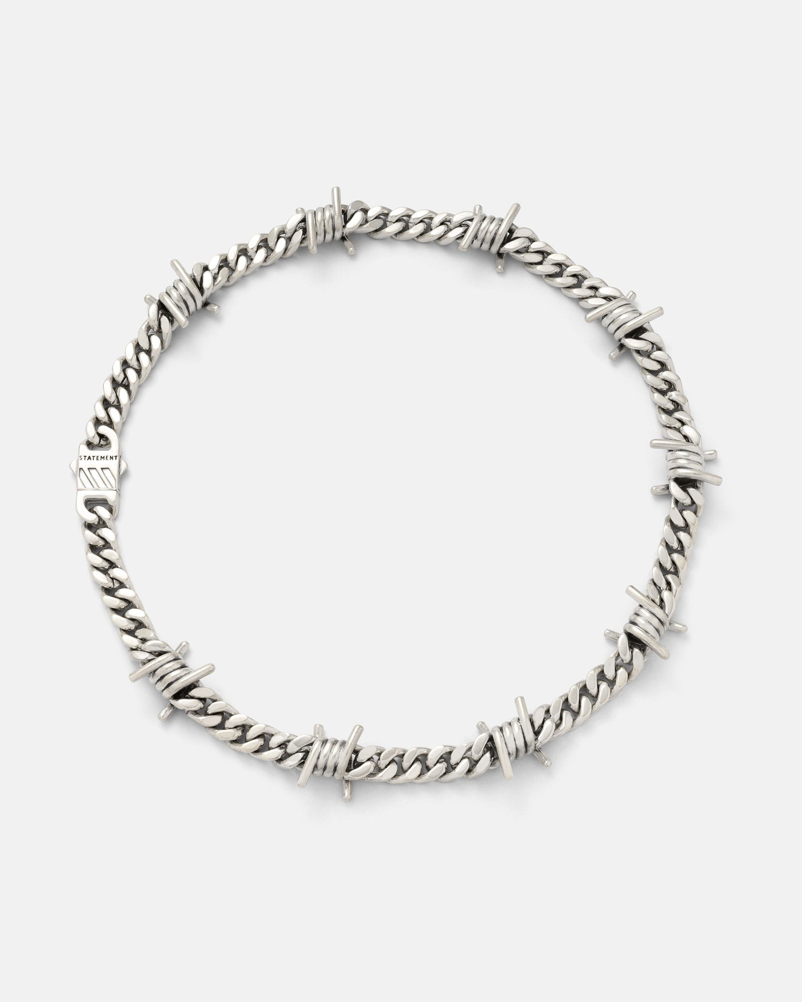 Silver barbed wire cuban chain on a light grey background by Statement Collective