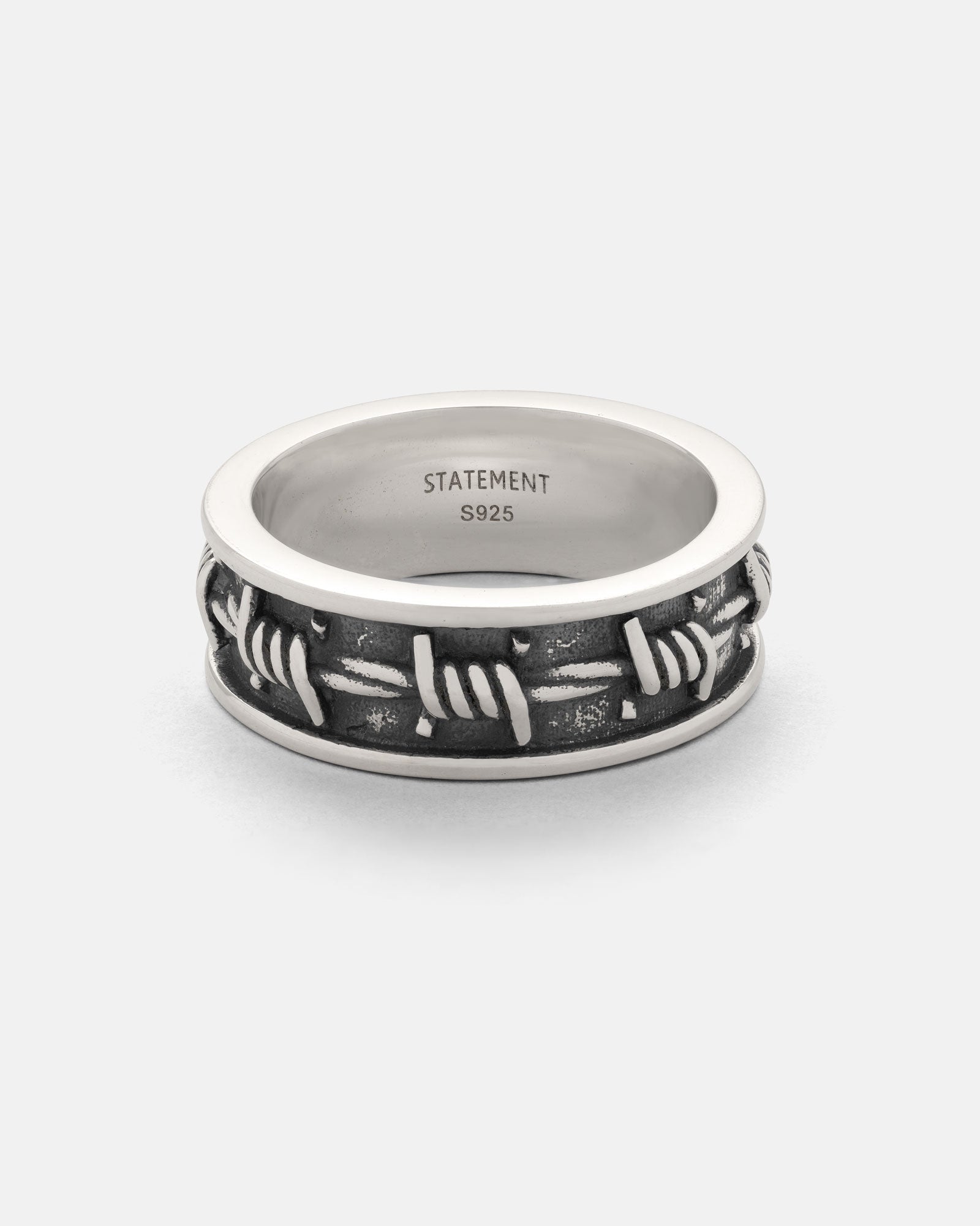 The 925 Sterling Silver Barbed Wire Ring features an engraved barbed wire design around the 3D band, with STATEMENT S925 stamped inside for authenticity.