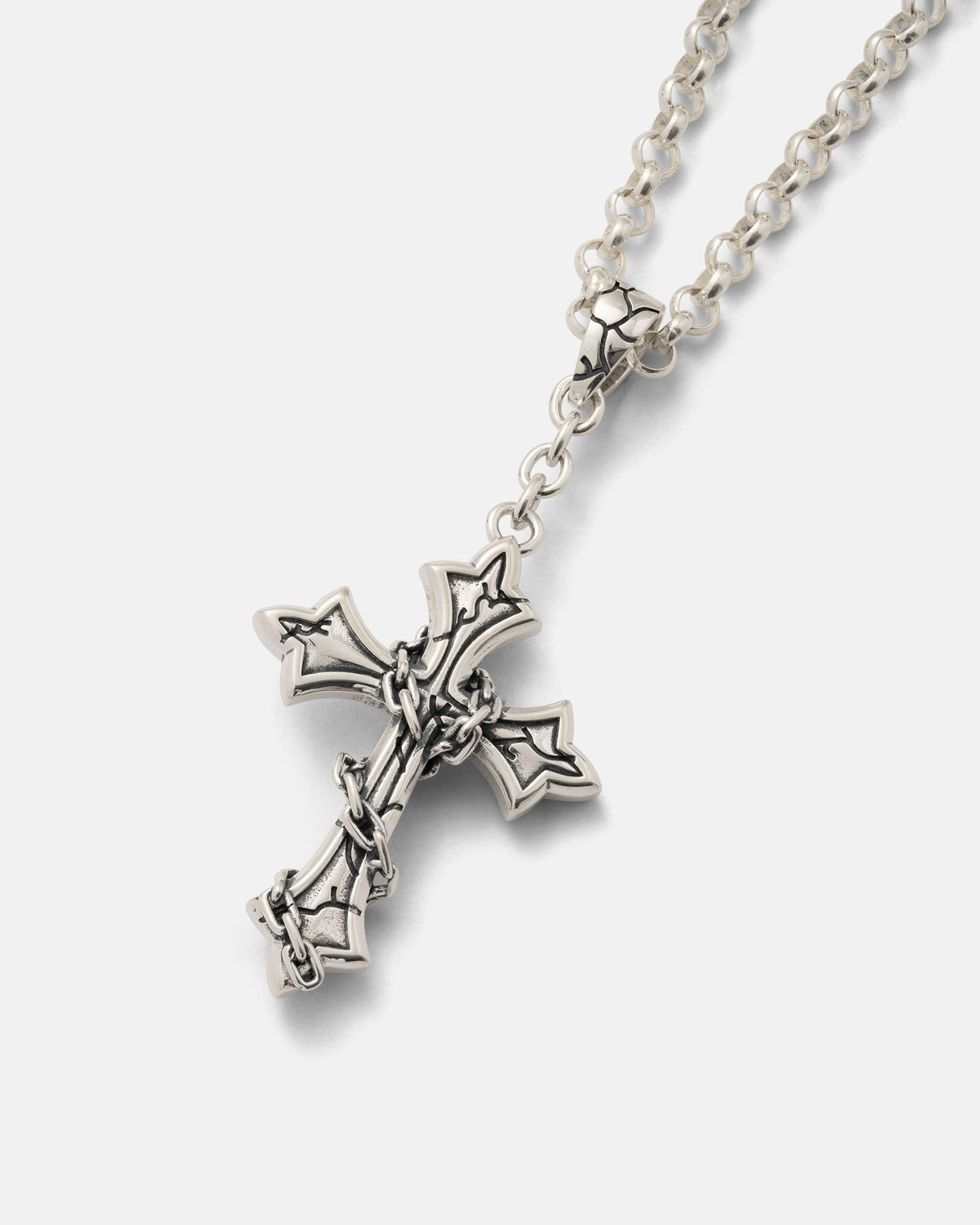 Introducing the 925 Sterling Silver Mini “The Ruins” Cross Pendant by Statement Collective—a bold gothic accessory. This striking pendant features a wrapped-chain design inspired by barbed wire and is showcased against a plain white background. It’s a compelling addition to any gothic jewelry collection.