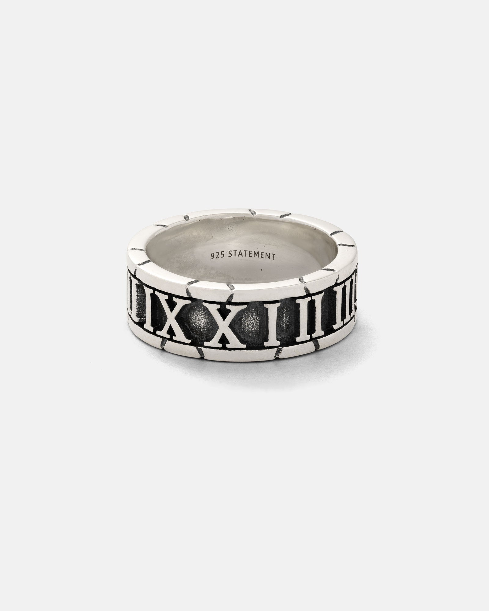 The 925 Sterling Silver Numerals Ring showcases engraved Roman numerals around the band and "925 STATEMENT" inscribed inside, presented on a plain, light gray background.