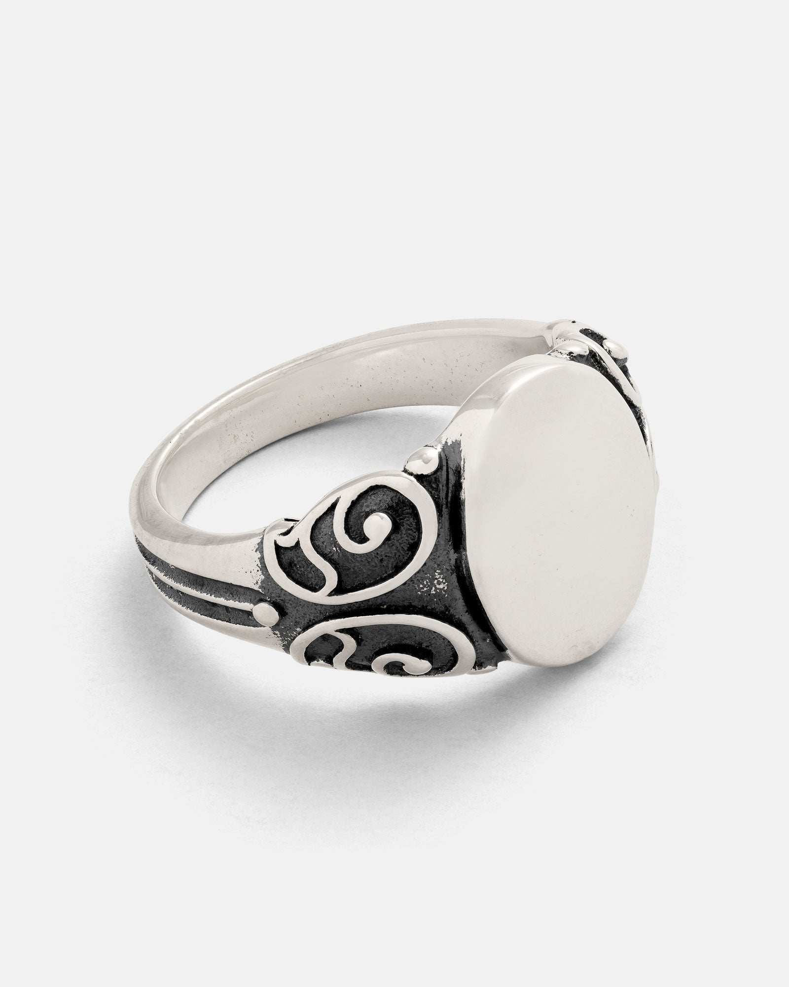The 925 Sterling Silver Mini Oval Scroll Signet Ring by Statement Collective is a handmade piece featuring a smooth, oval-shaped top and detailed blackened scroll designs on the band, displayed against a plain white background.