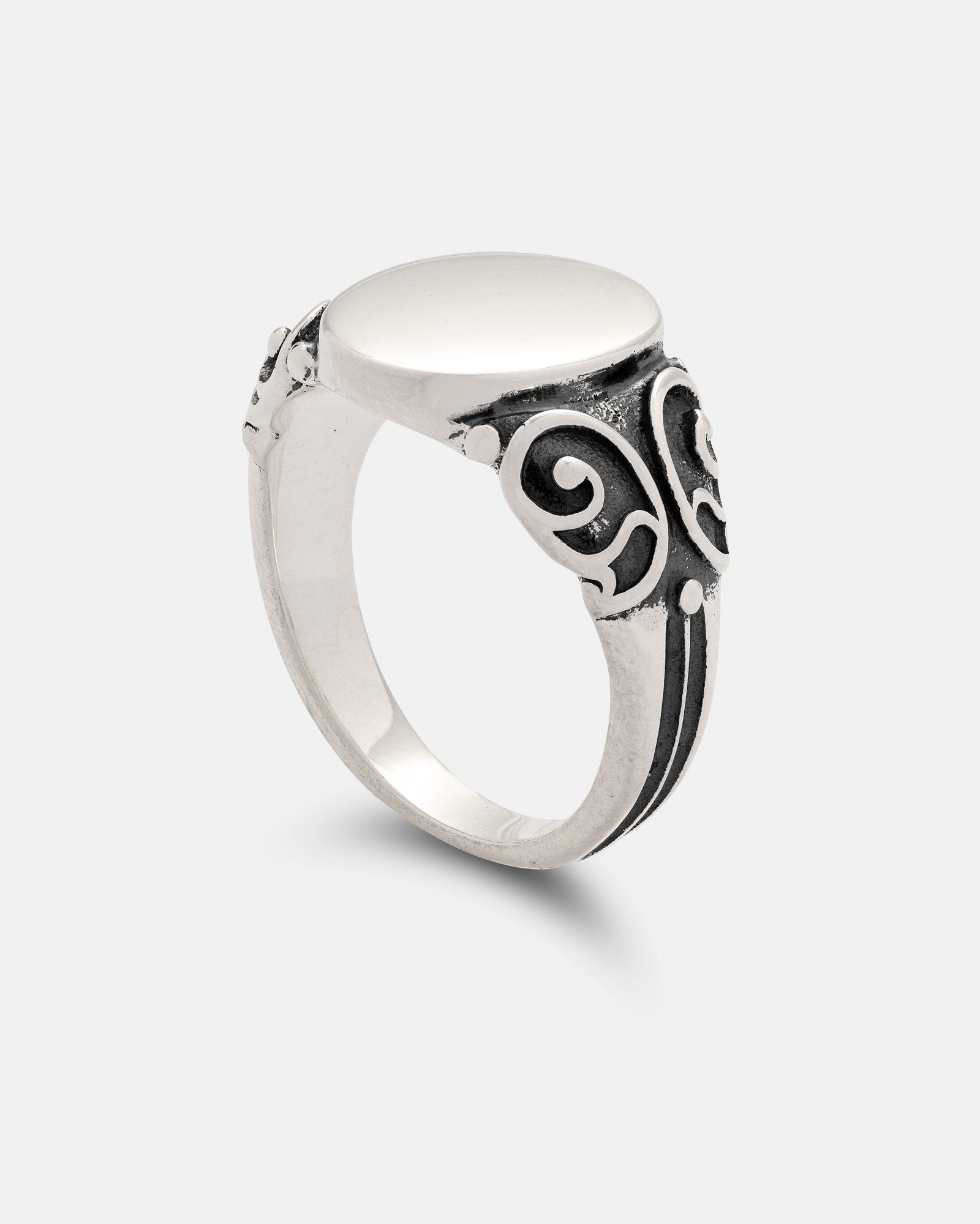 Showcased against a light gray background, the Statement Collective 925 Sterling Silver Mini Oval Scroll Signet Ring features a handmade oval top complemented by intricate black engraved scrollwork along the sides.