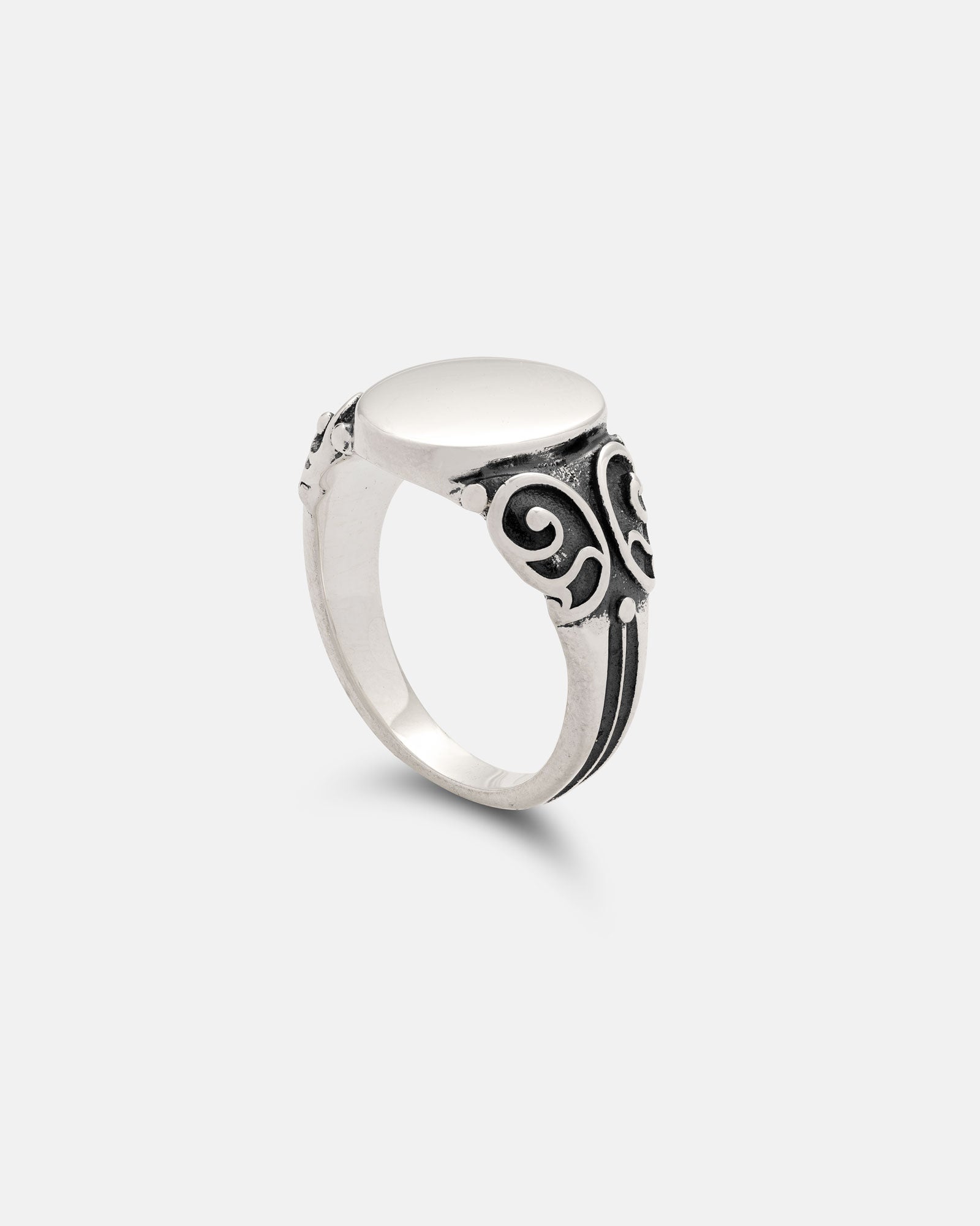 The 925 Sterling Silver Mini Oval Scroll Signet Ring features a smooth, flat oval top and ornate blackened swirl designs on the band, displayed against a simple light gray background.