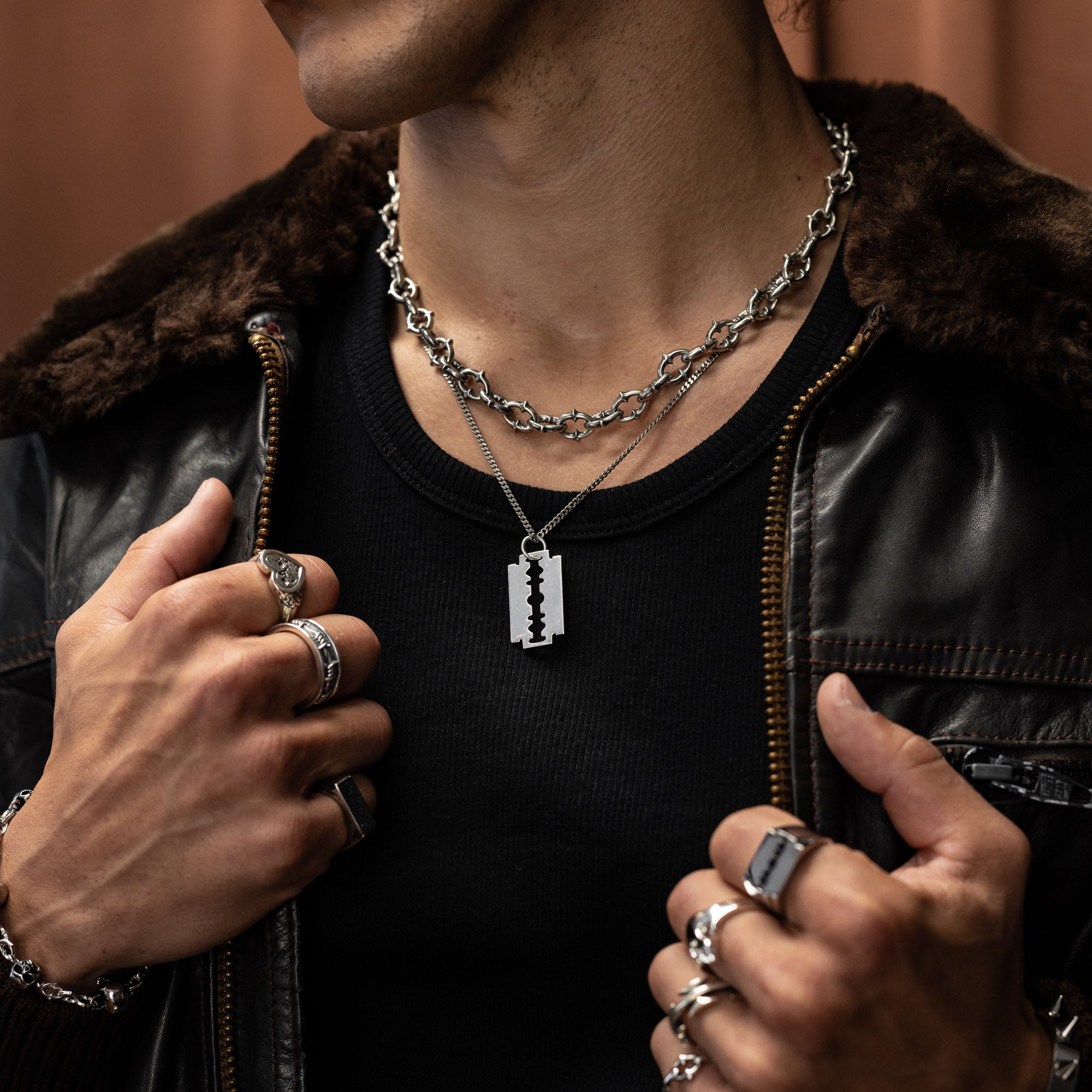 sterling silver razorblade pendant hallmarked with s925 on model's neck against brown background