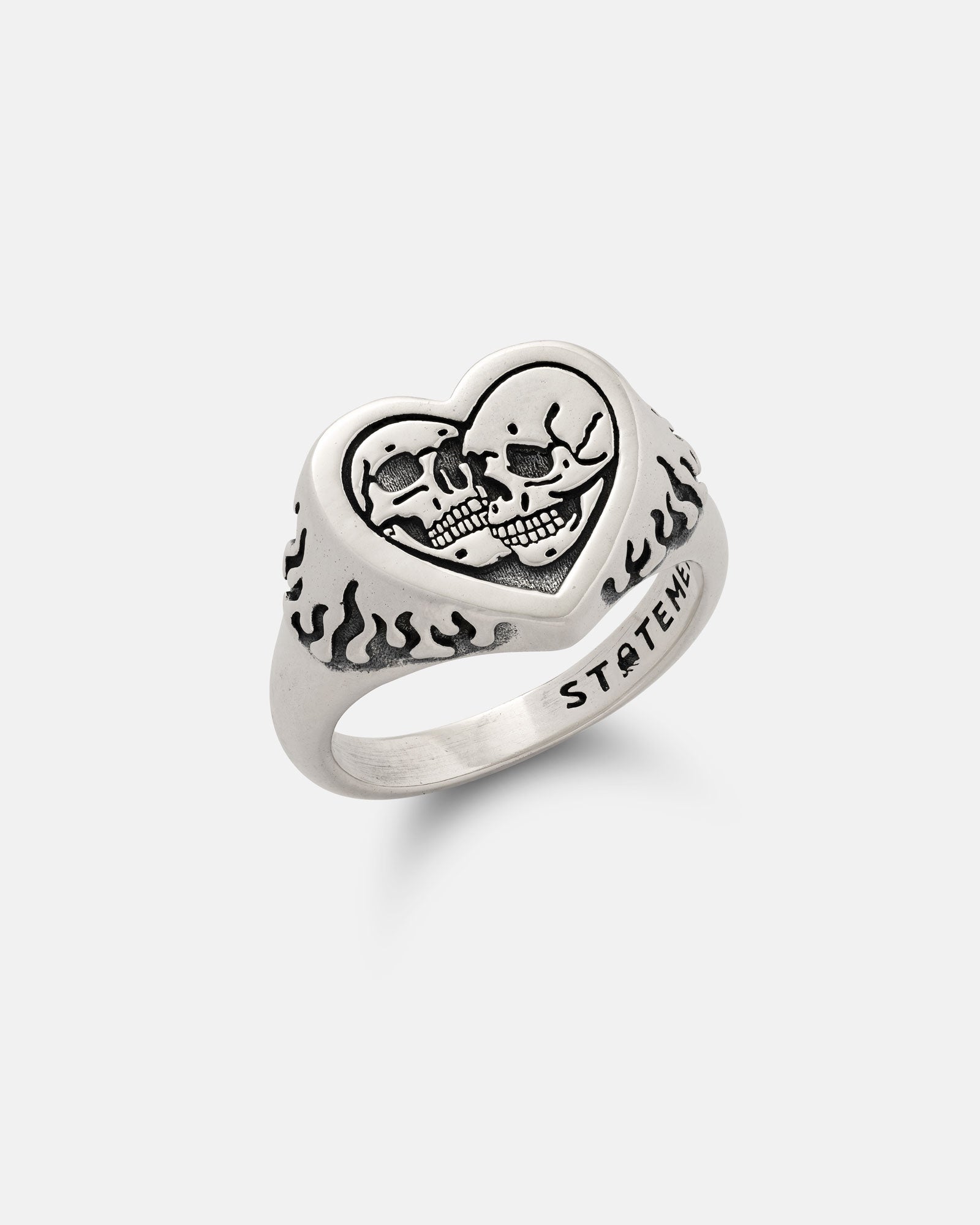 The 925 Sterling Silver Skull Heart Ring features a heart-shaped face with two engraved skulls, flame designs on the band, and "STATEMENT" etched on the side.