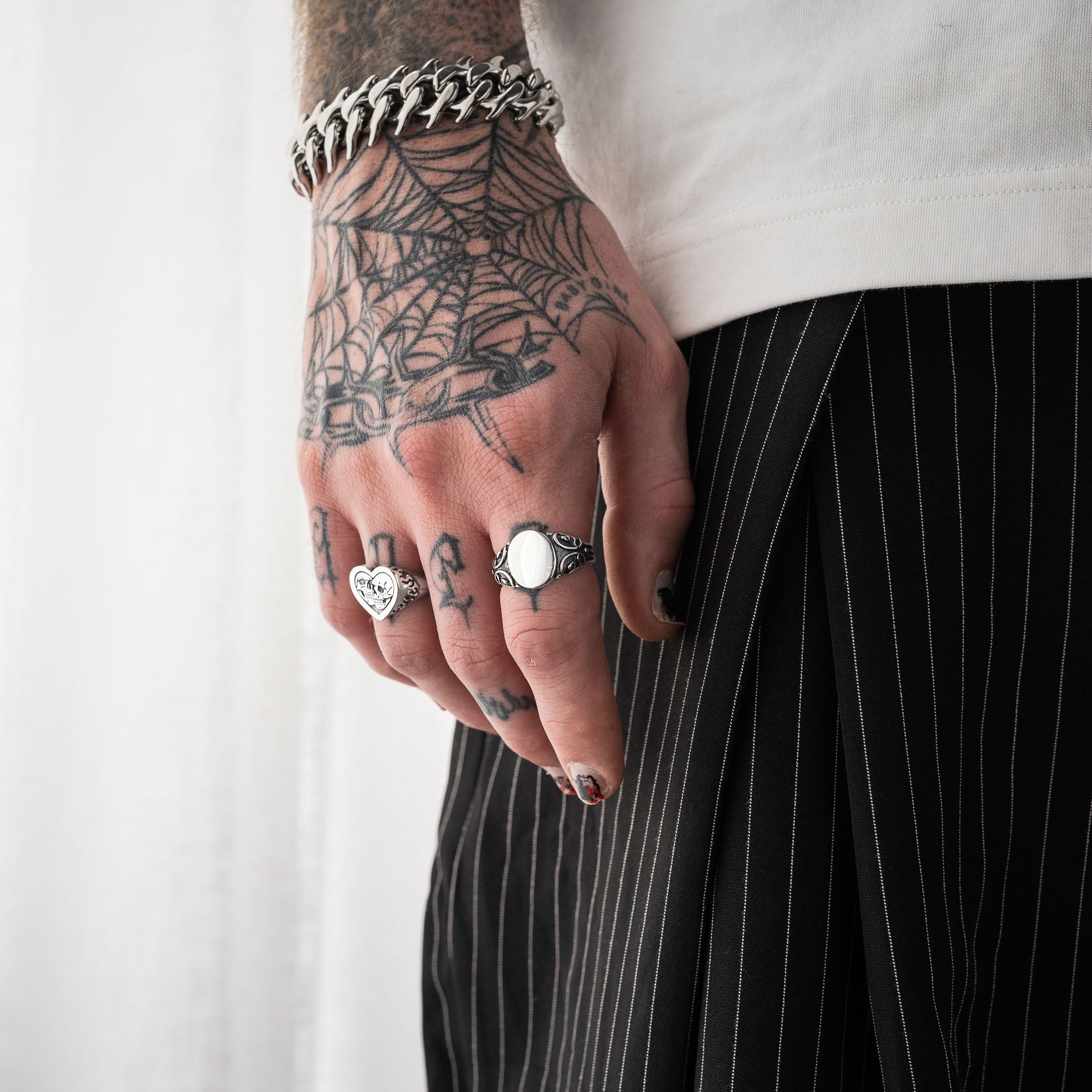 Tattooed men's hand wearing 925 sterling silver scroll signet ring by statement collective
