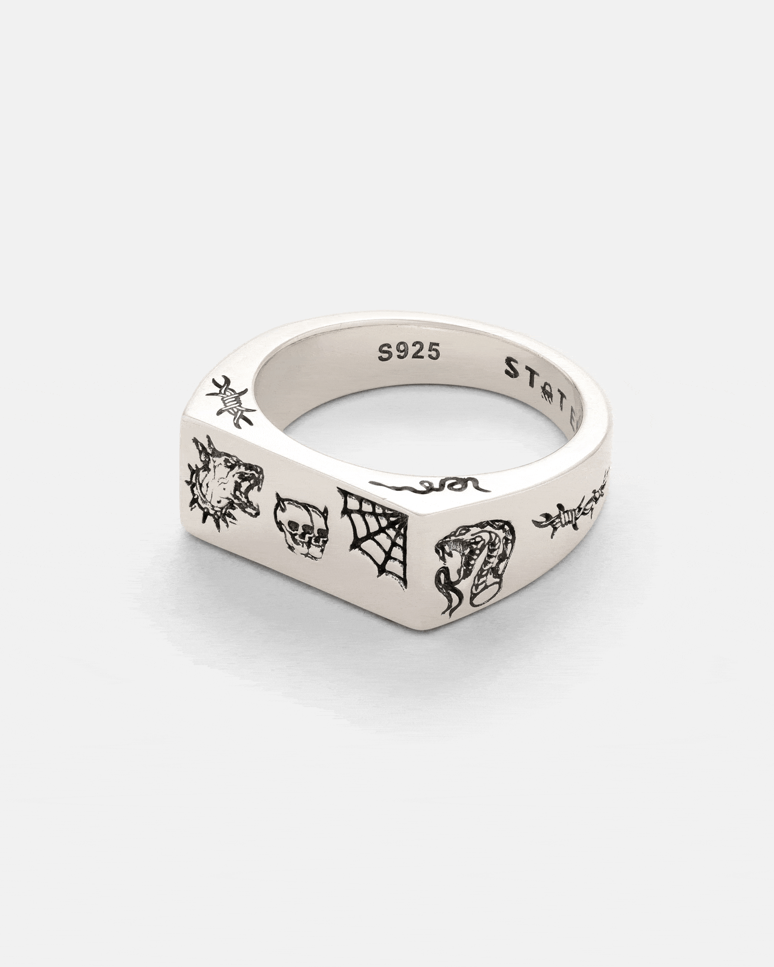 The Statement Collective 925 Sterling Silver Tattoo Signet Ring features a square shape with black laser-engraved tiger, skull, spider web, snake, and barbed wire designs. The inner band is stamped S925 for authenticity.