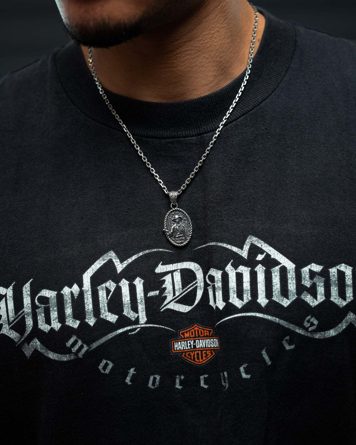 A person wearing a black Harley-Davidson Motorcycles t-shirt and a 925 Sterling Silver “Big Iron” Pendant by Statement Collective, styled with bold punk metal jewelry. The image is cropped to show only the neck and upper chest.