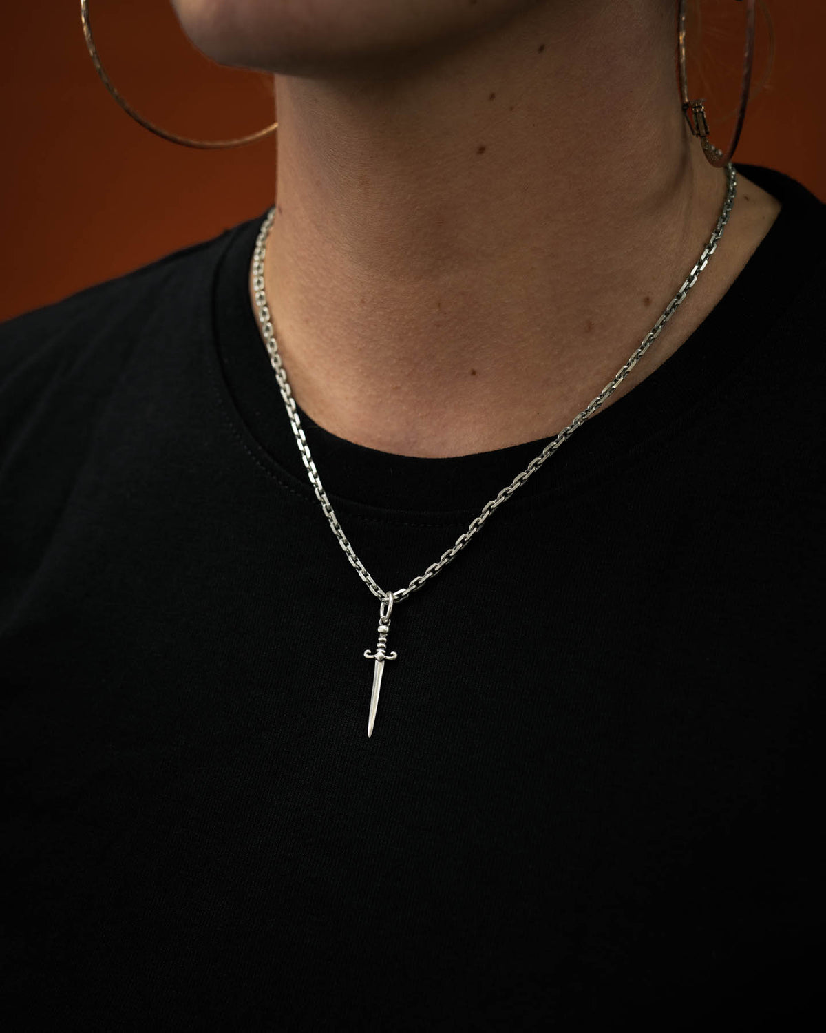 mini dagger pendant in 925 sterling silver on women's neck again orange background