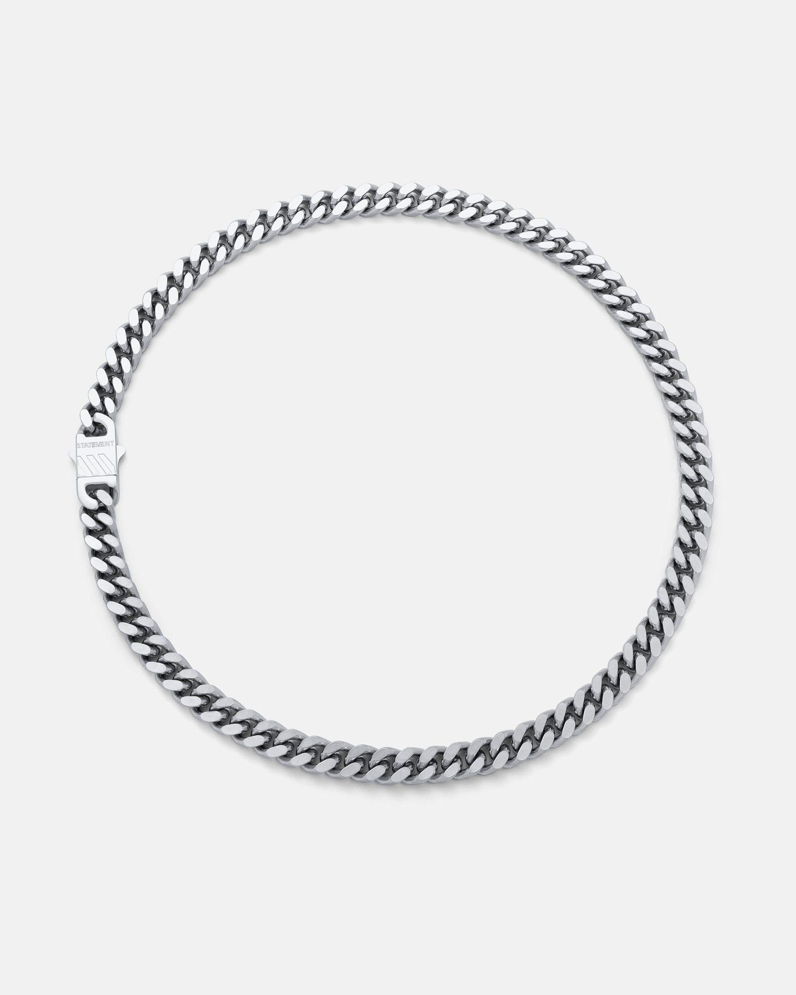 The 9mm Cuban Chain, in silver with a flat clasp, is displayed in a circular shape on a plain light gray background.