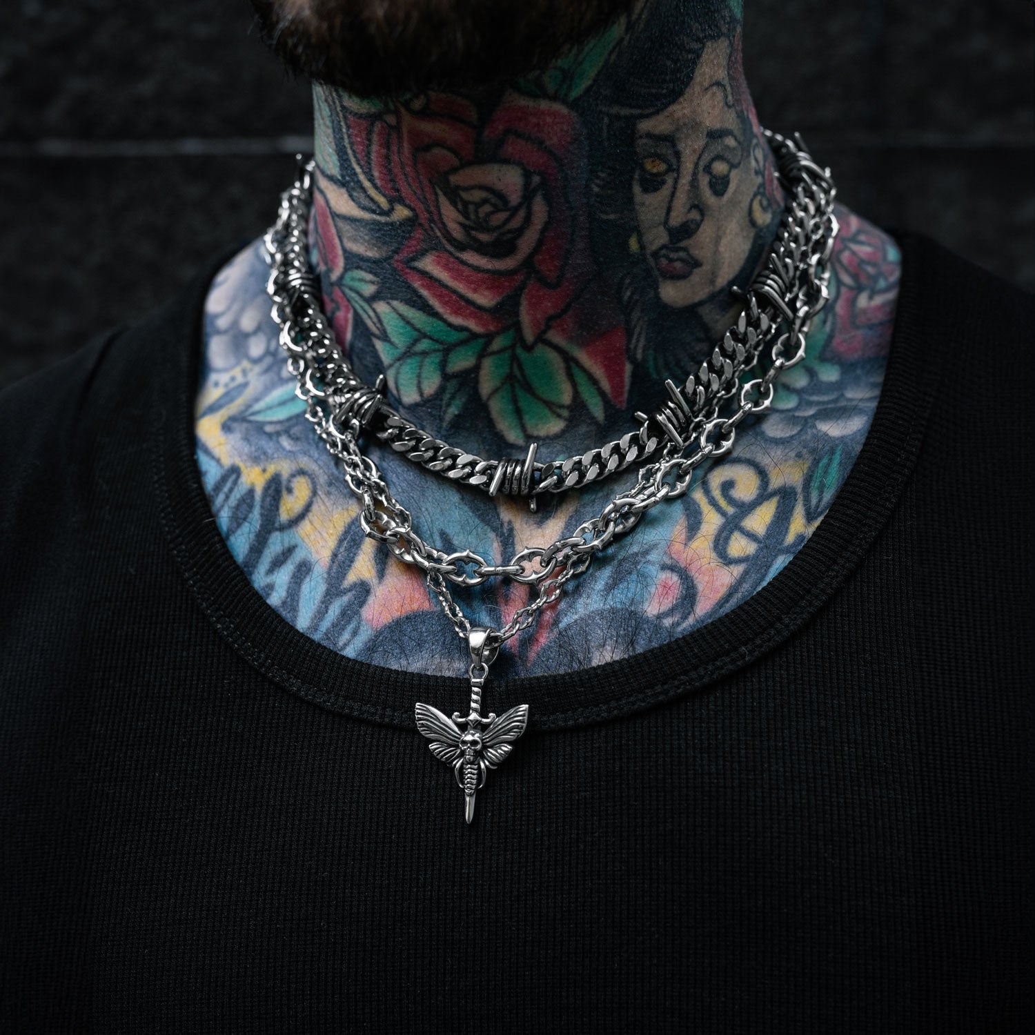 Gothic silver chain set with moth and dagger pendant and barbed wire chain on mans neck by Statement Collective