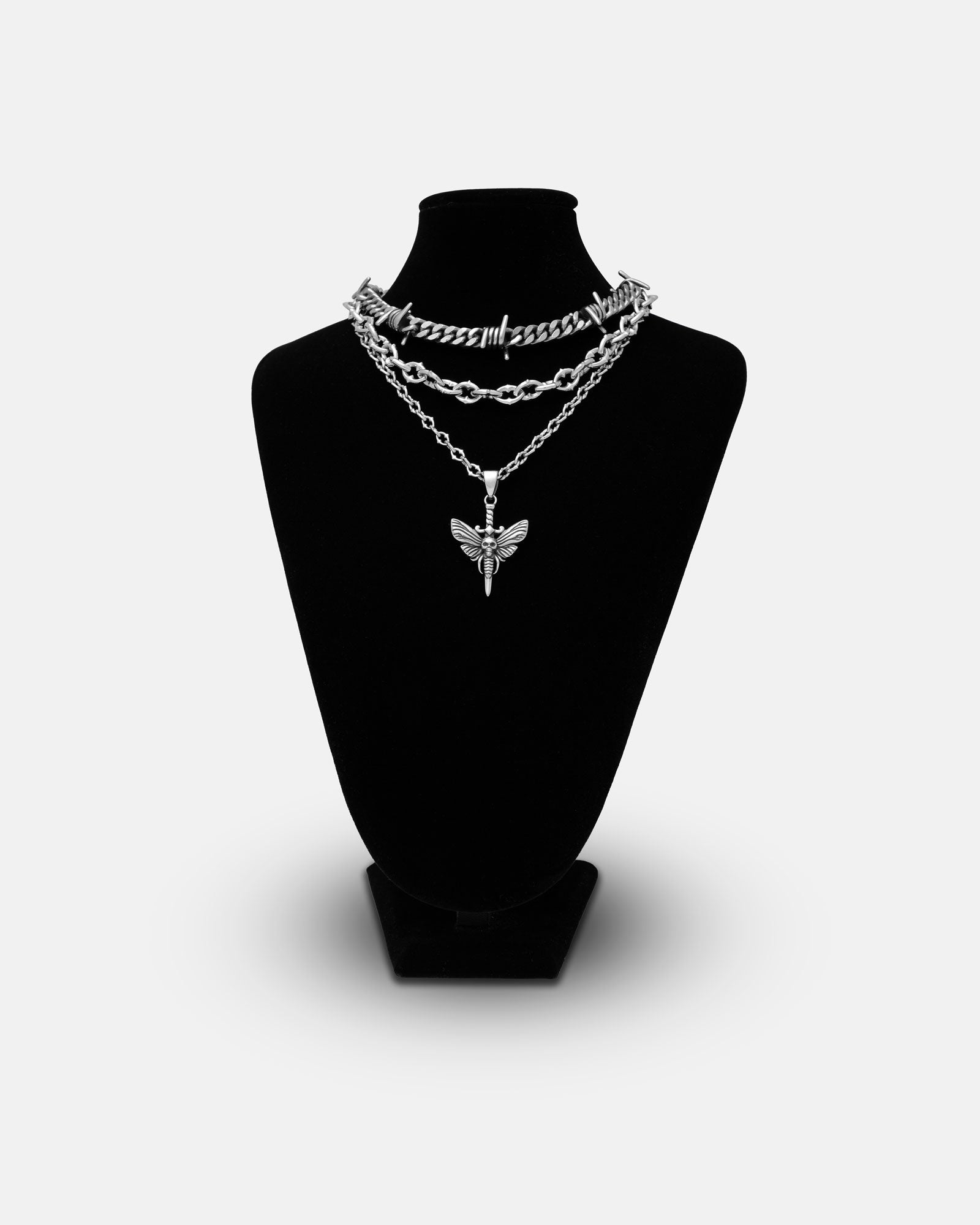 The Spite Stack (Custom Pendant Choice) features three silver chains on a black velvet display, including an aggressive chain with a butterfly pendant, all set against a plain white background.
