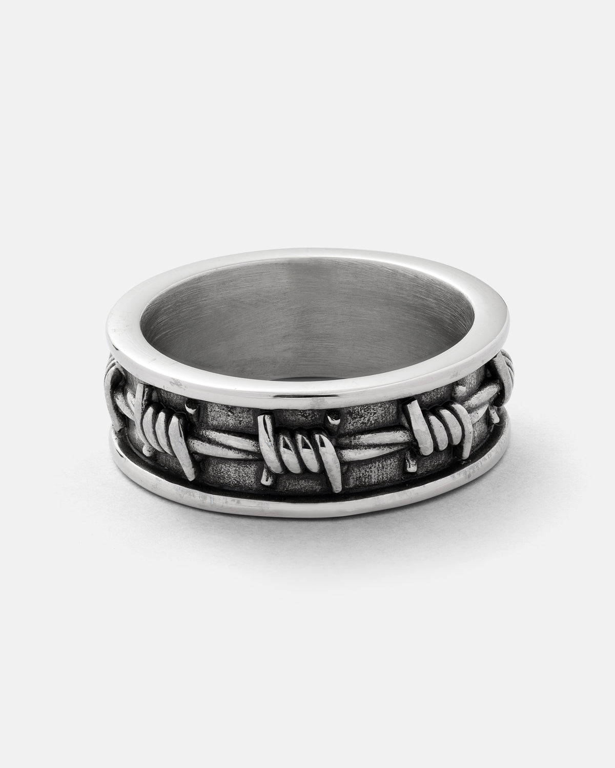 The Statement Collective Barbed Wire Ring showcases a raised barbed wire design encircling its 316L stainless steel band, displayed on a plain white background.