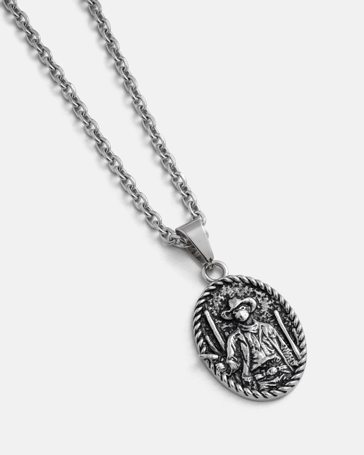STATEMENT "Big Iron" Pendant: A silver chain necklace with an oval stainless steel pendant engraved with an image of a man wearing a hat, framed by two vertical elements, displayed on a plain white background.