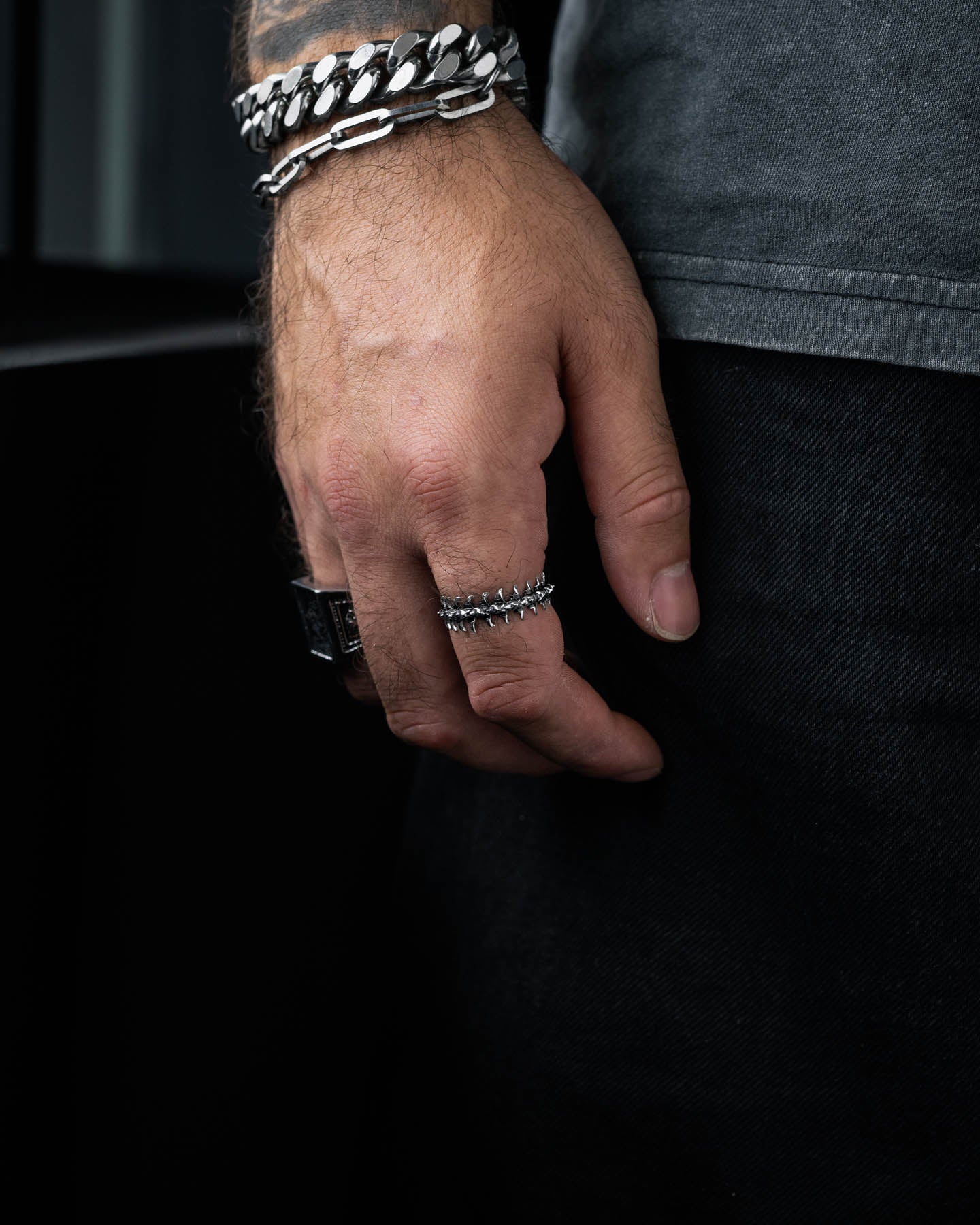 mans hand wearing band ring with fishbone pattern around the design