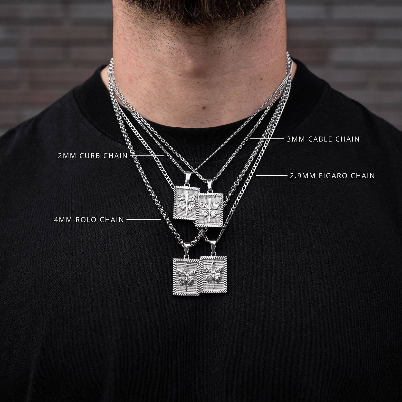 Man wearing multiple butterfly necklaces with chain types labeled against a brick wall background