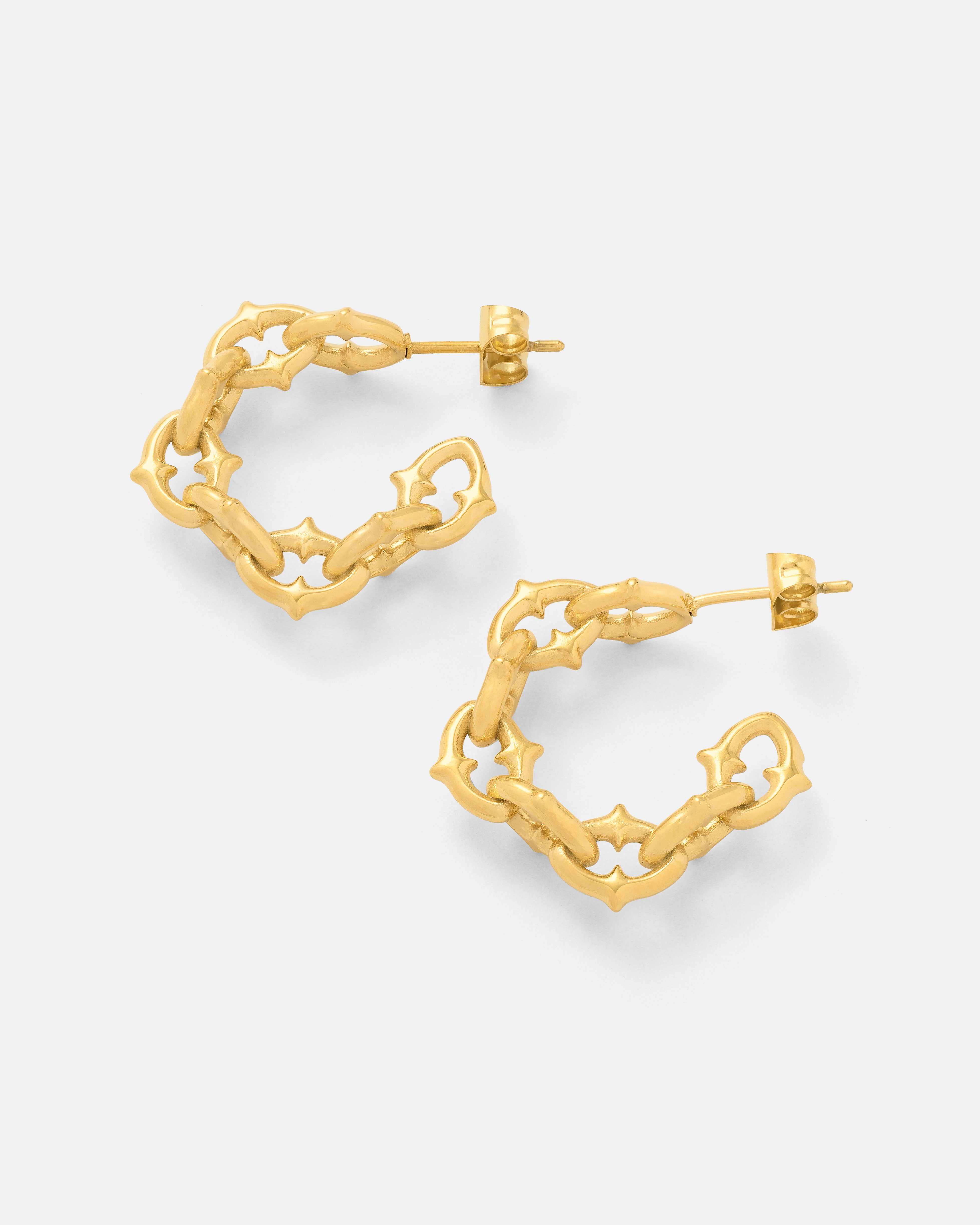 Introducing "The Cathedral" Hoop Earrings (Gold): 18k gold-plated hoops featuring a chunky geometric chain design, subtle spiked cathedral links, and star-shaped cutouts, shown on a plain white background.