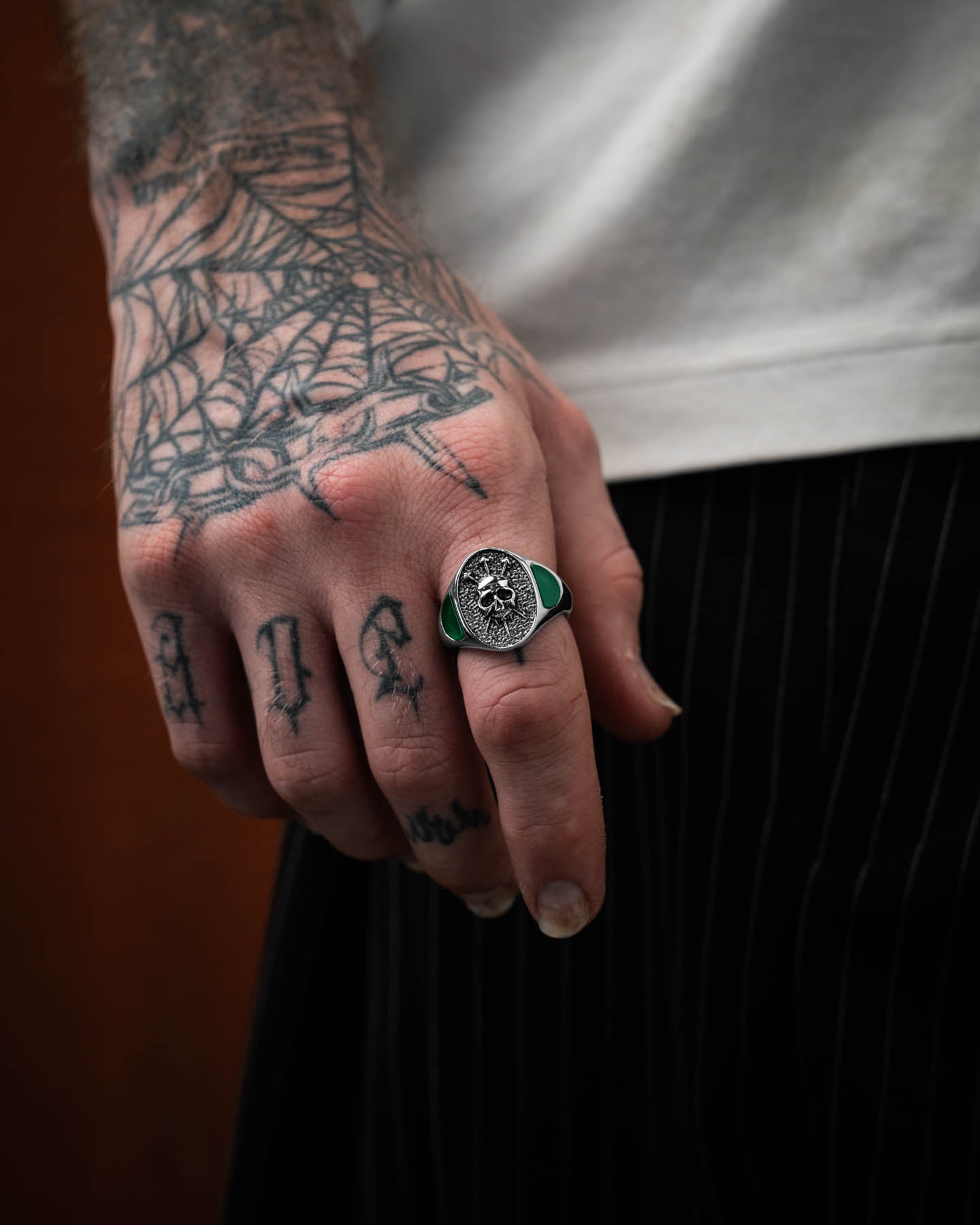 signet ring with skull and green stones on models hand by statement collective