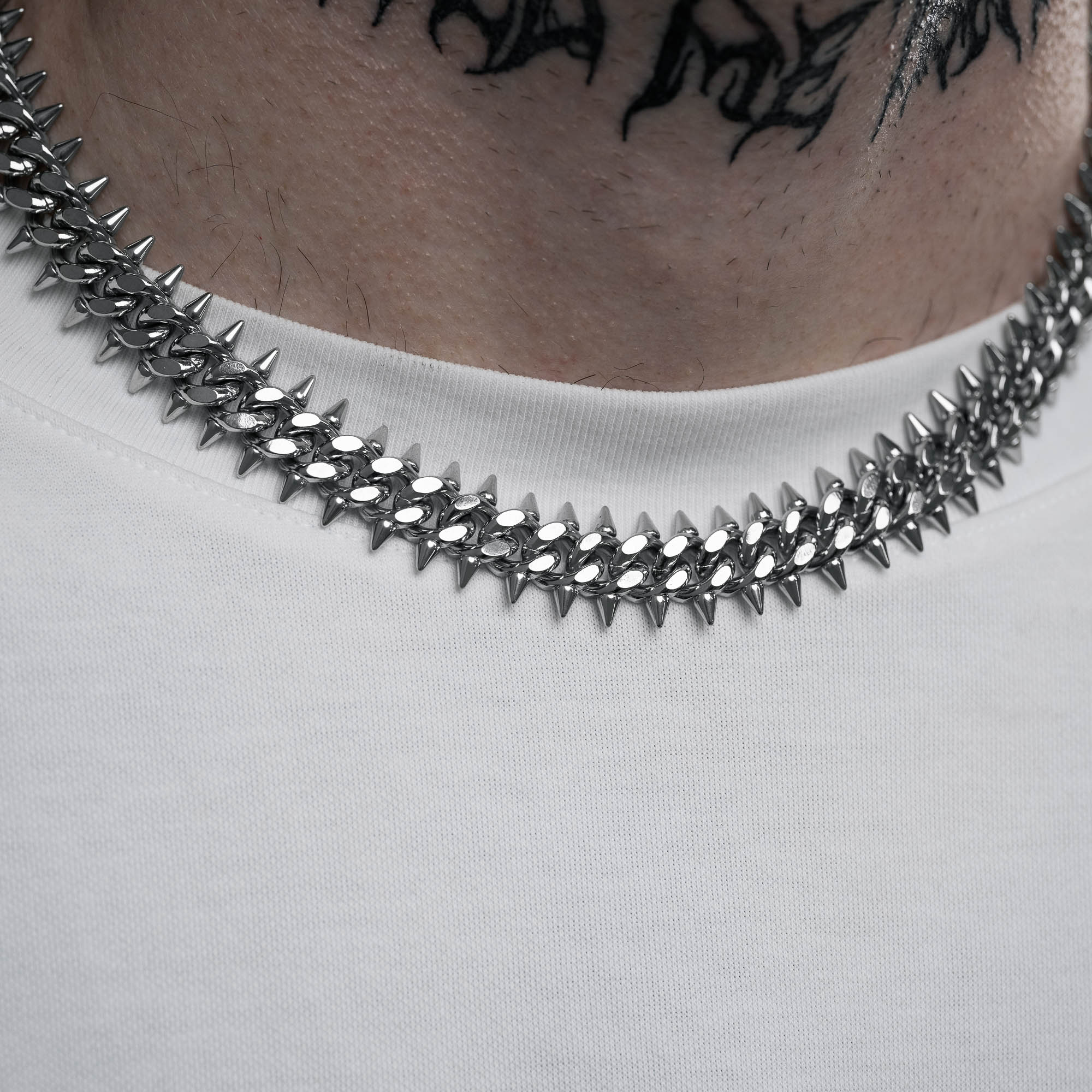Silver 9mm Cuban chain with spikes on every link, on male model with neck tattoo
