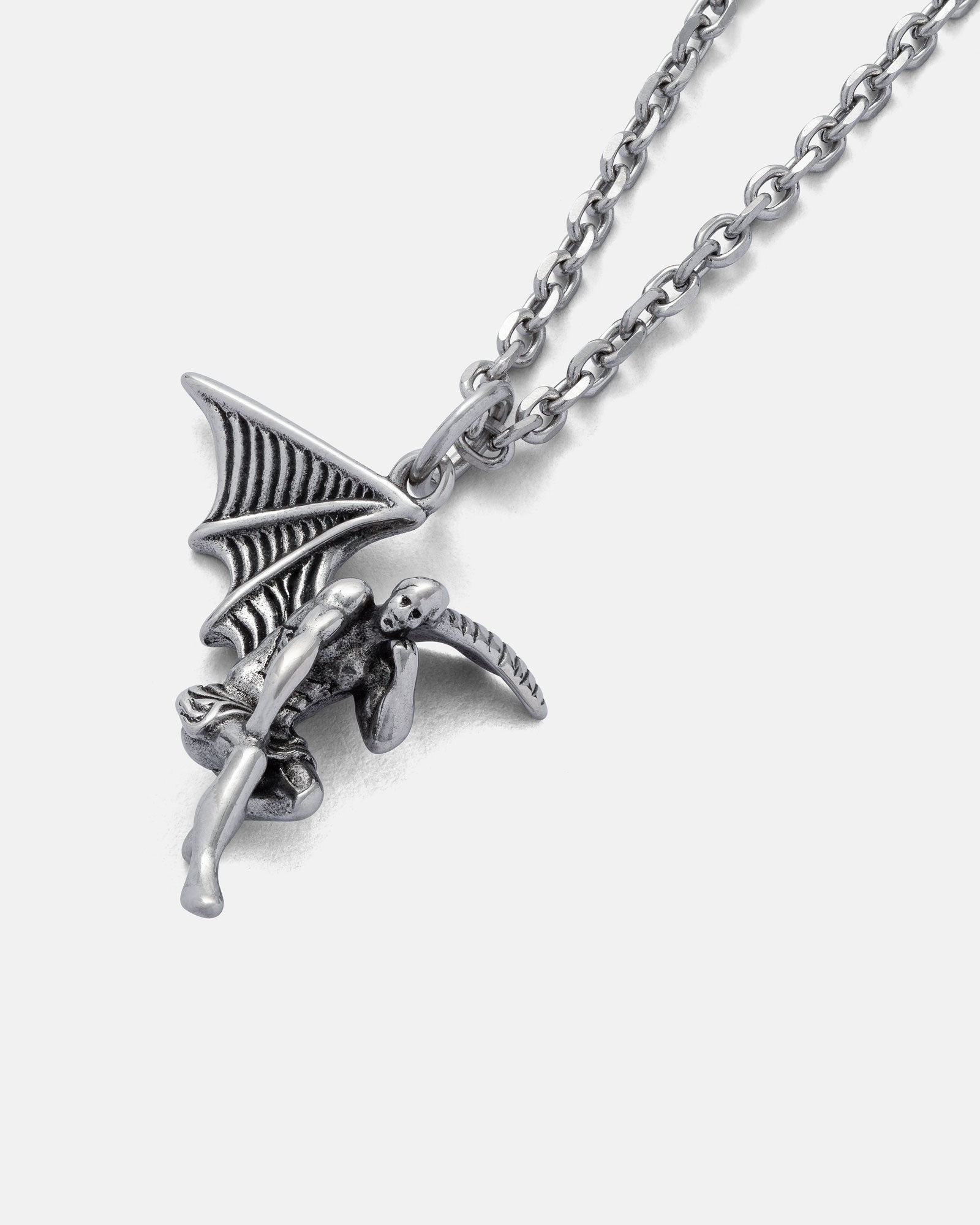 The Fallen Angel Pendant is a silver necklace chain with a seated, bat-winged figure and long tail, creating a striking and unique jewellery piece. Displayed on a plain white background.