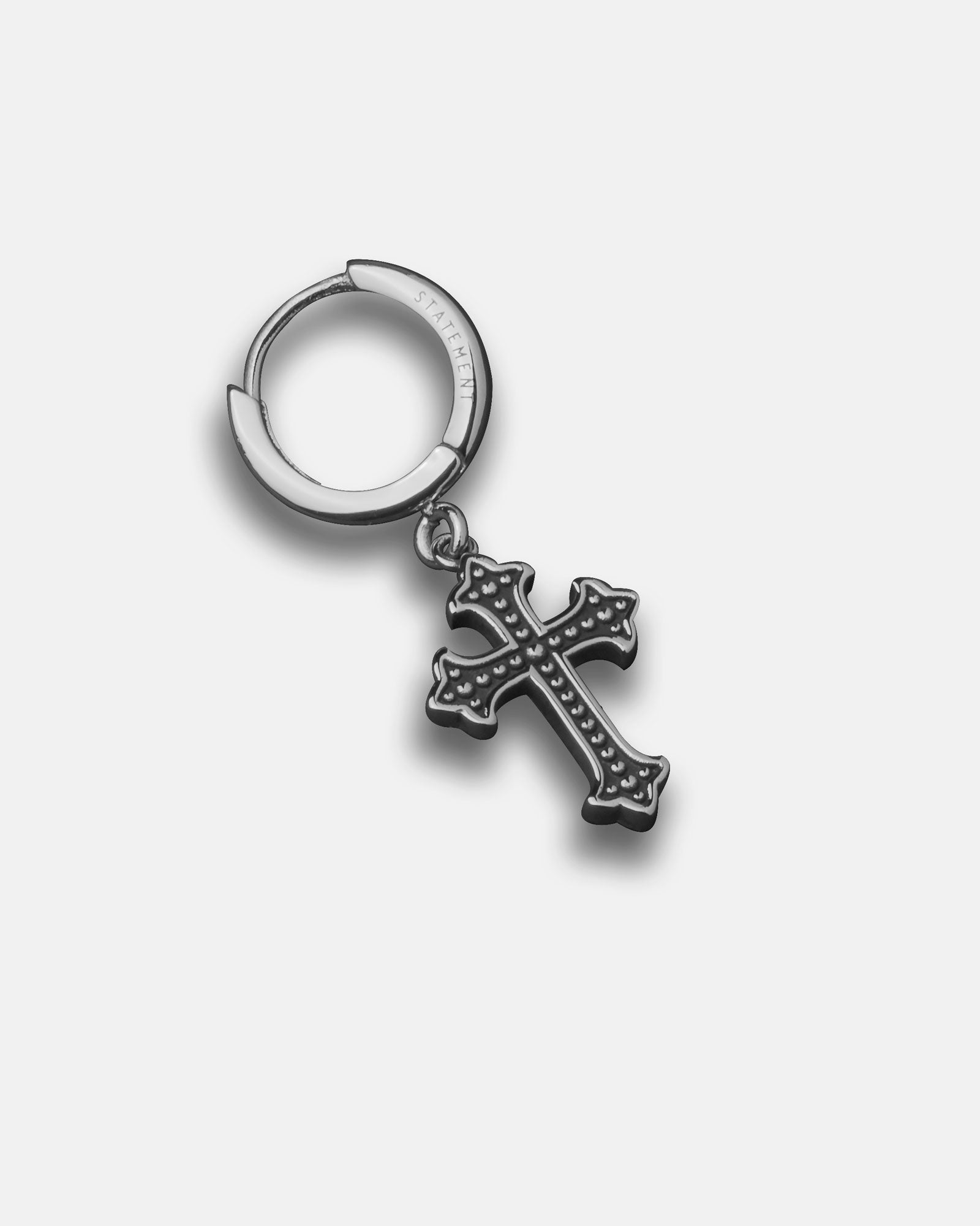 The French Cross Earring features a silver hoop with a dangling, ornate black cross pendant adorned with small raised dots, perfect for those seeking stylish men's cross earrings. Displayed on a plain white background.