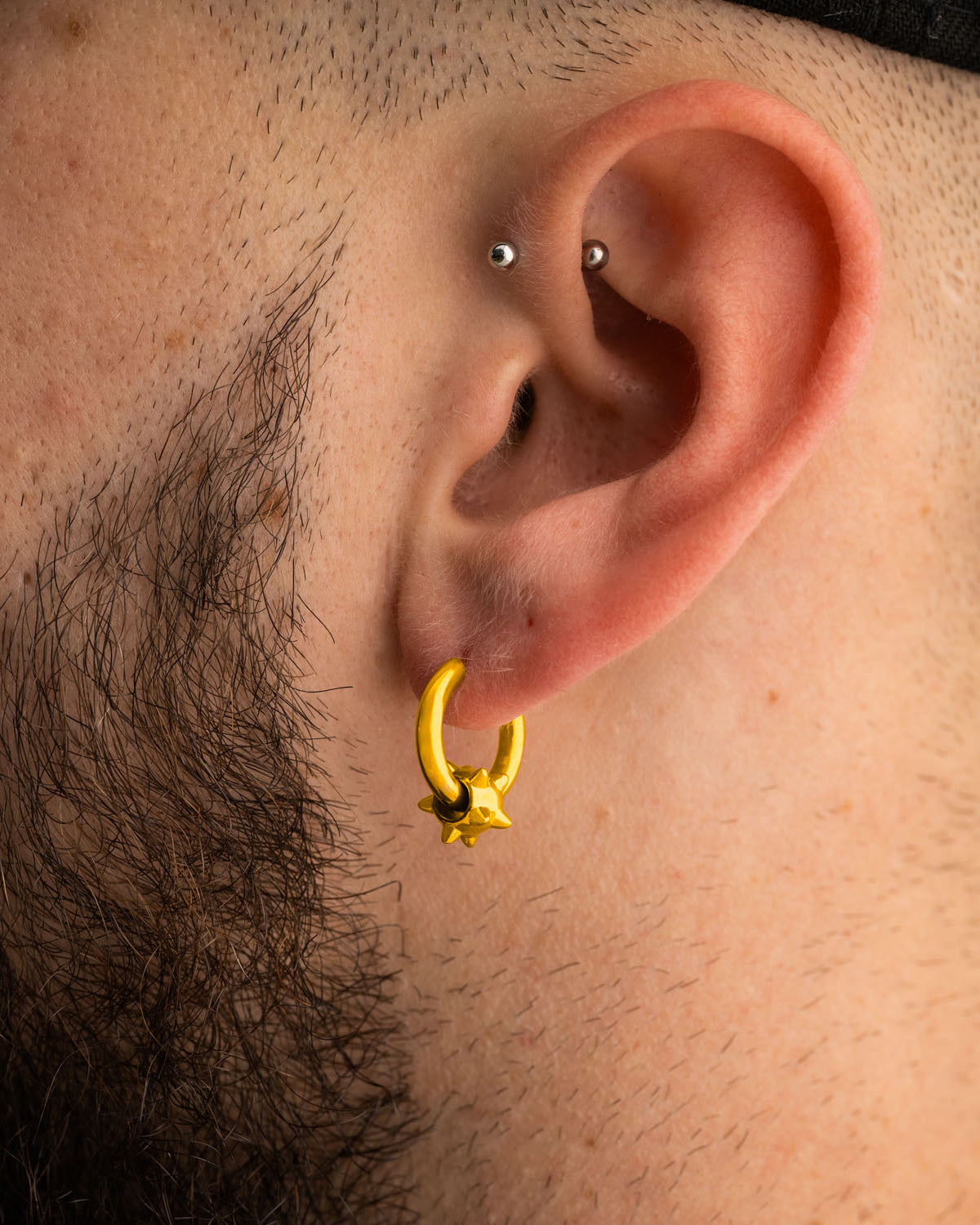 Statement Collective Morning Star Earrings (Gold) featuring an 18k gold plated hoop with a small, star-shaped charm worn in an earlobe piercing.