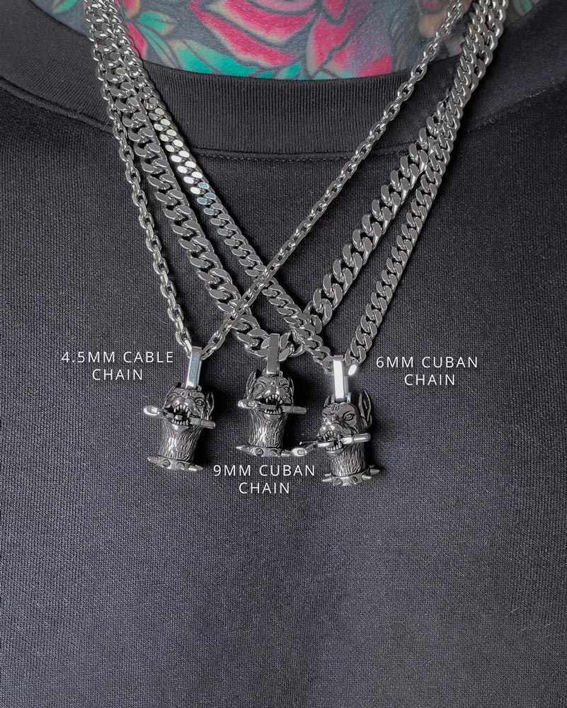 A close-up of three "The Guard Dog" pendants by Statement Collective, on 4.5mm cable, 6mm Cuban, and 9mm Cuban stainless steel chains, displayed on a black shirt.
