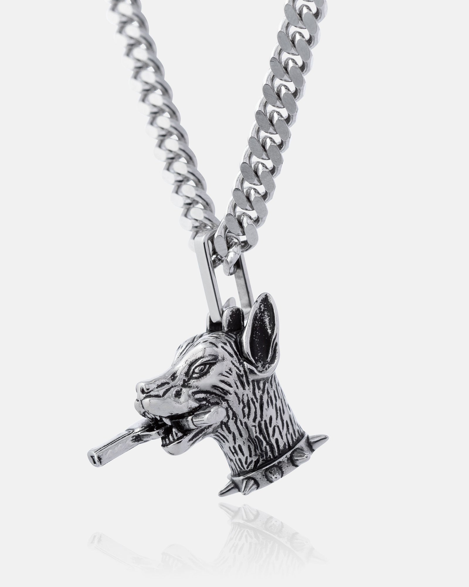 The Guard Dog" Pendant is a silver street necklace with a Doberman dog's head, spiked collar, and cigar in its mouth—an edgy hip hop jewelry piece shown against a plain white background.