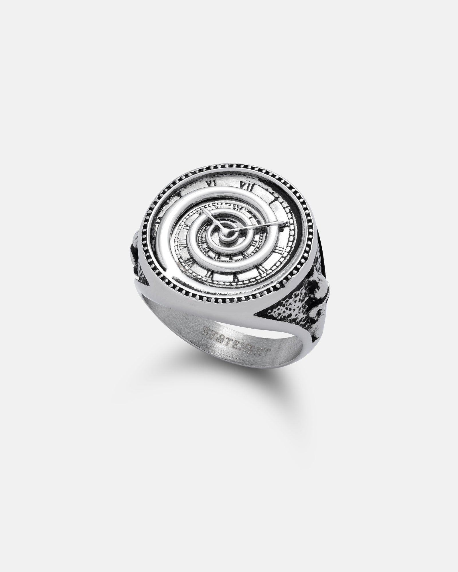 The Statement Collective Infinite Clock Ring features an intricate spiral clock face with Roman numerals and engraved details, inspired by ancient astronomical clocks, and is shown on a white background.