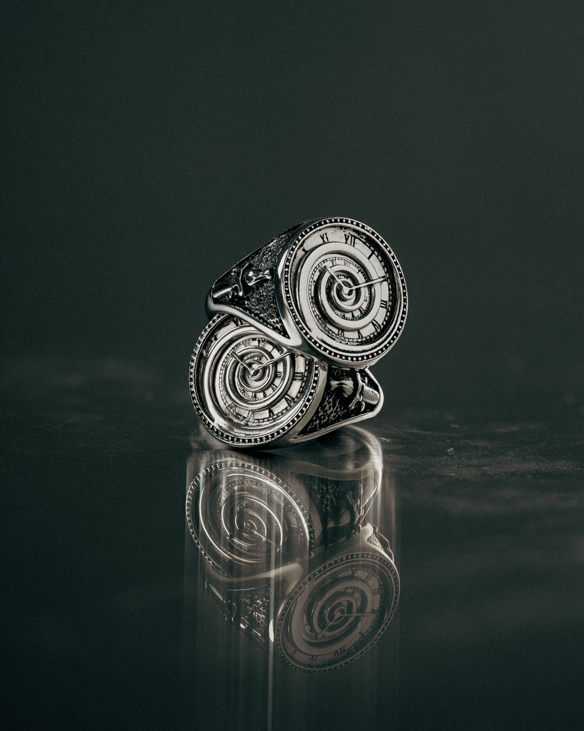 silver spiral clock ring on reflective surface
