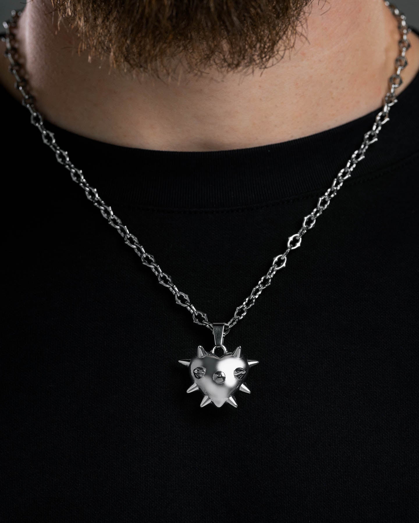 Wearing the "Love Hurts" Spiked Heart Pendant—a shiny, silver chain necklace with a spiked heart design—adds edgy grunge style to any black shirt.