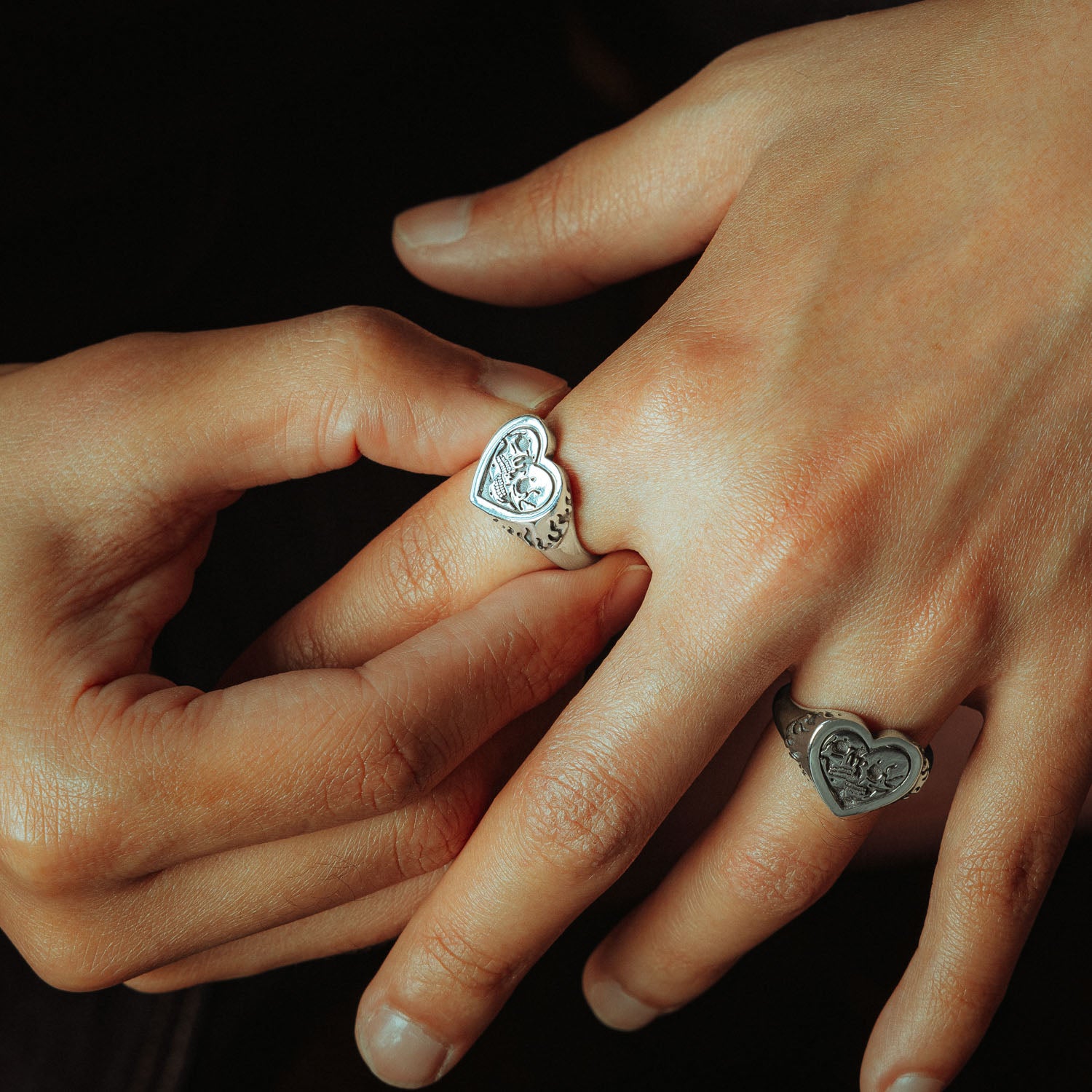 Sterling Silver heart shaped ring with skulls and flames on male hands