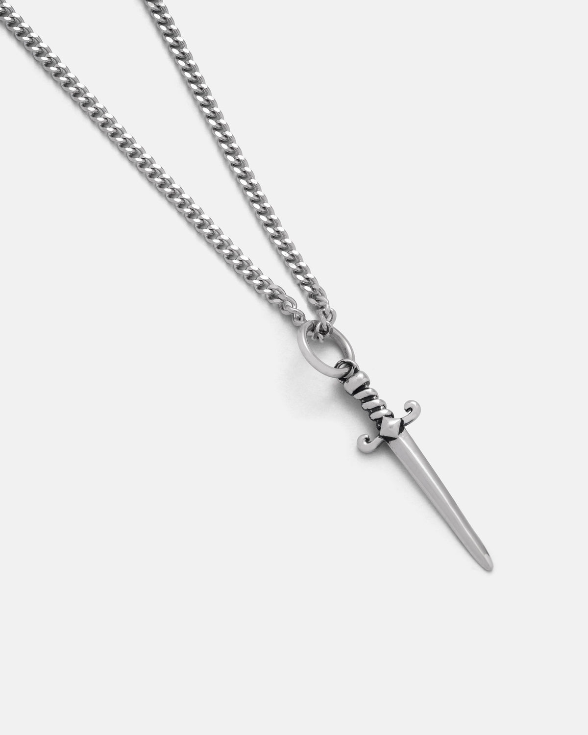 The Statement Collective Mini Dagger Pendant is a silver necklace featuring a dagger-shaped pendant on a curb chain, capturing the allure of dark romance jewelry, displayed against a plain white background.
