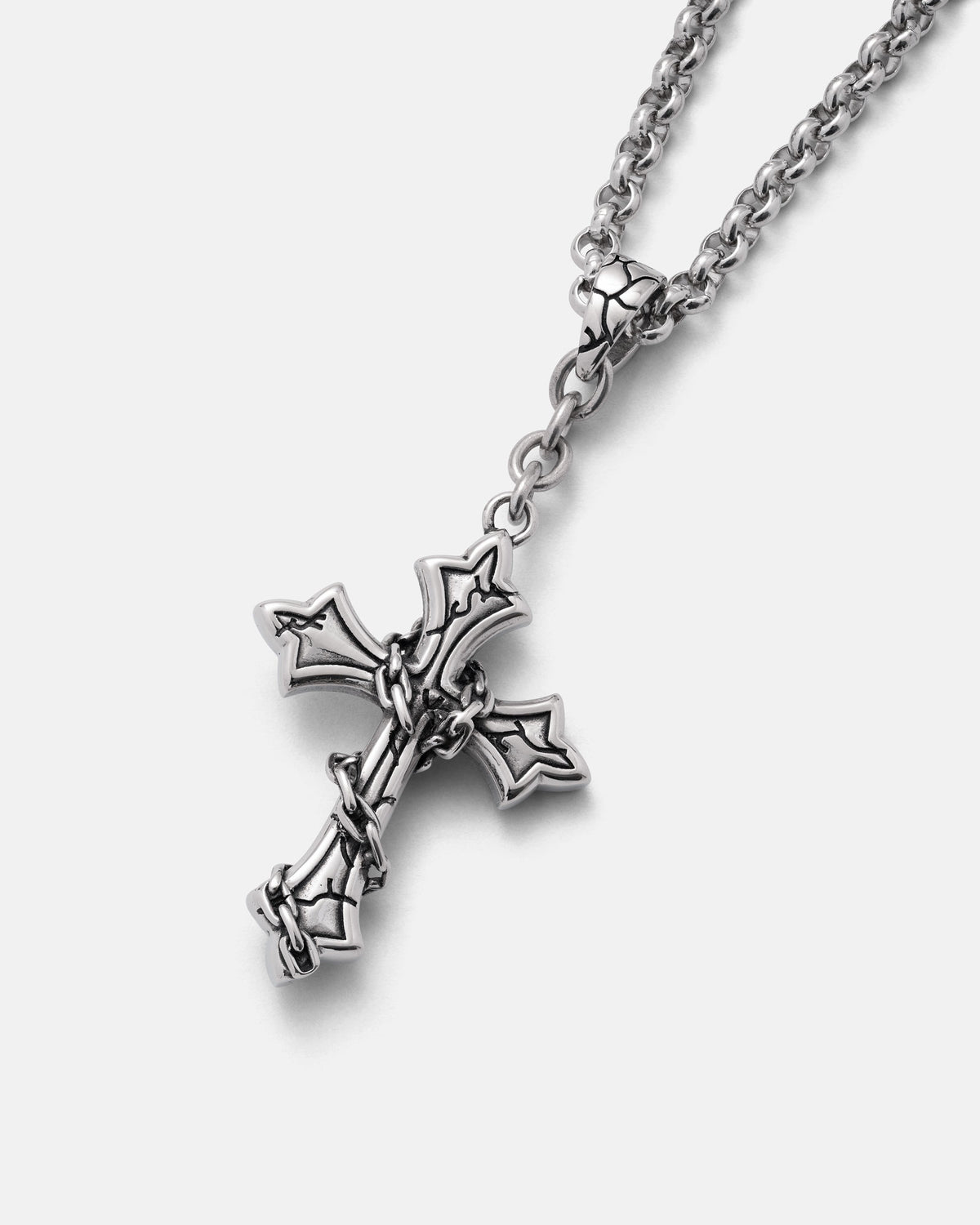 The Mini “The Ruins” Cross Pendant by Statement Collective is a striking silver chain necklace featuring a detailed gothic cross wrapped in barbed wire, showcased against a plain light background—an edgy yet timeless piece crafted from stainless steel.
