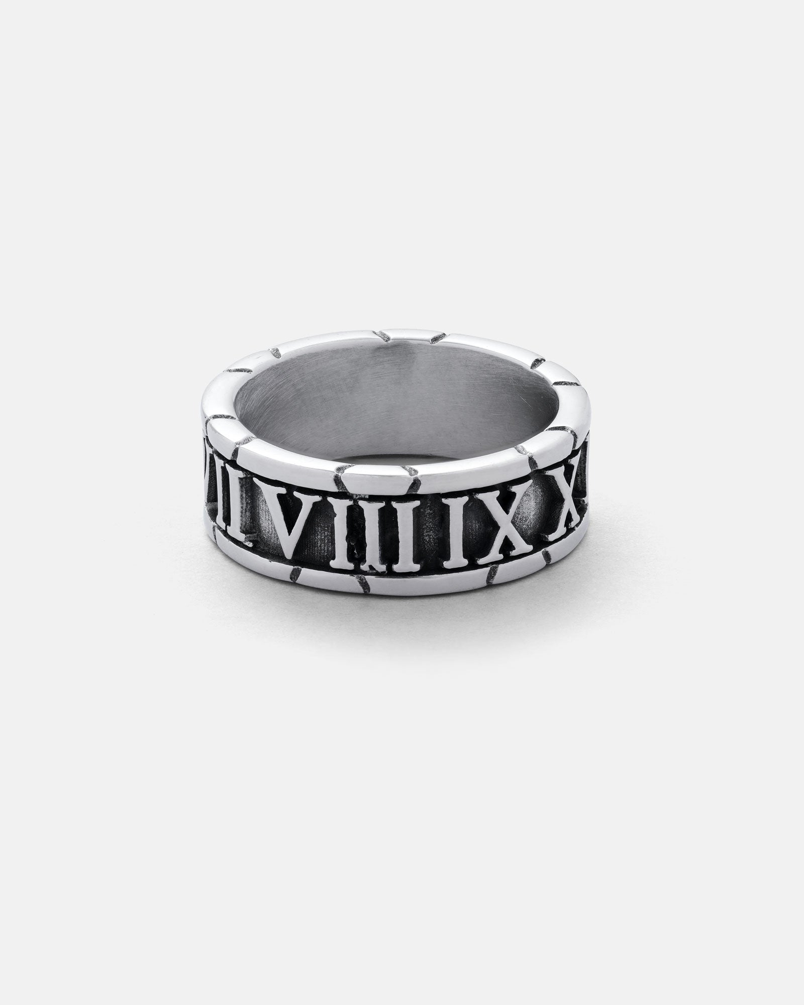 The Numerals Ring is a stainless steel band engraved with black Roman numerals, ideal for stacking. Shown on a simple light gray background.