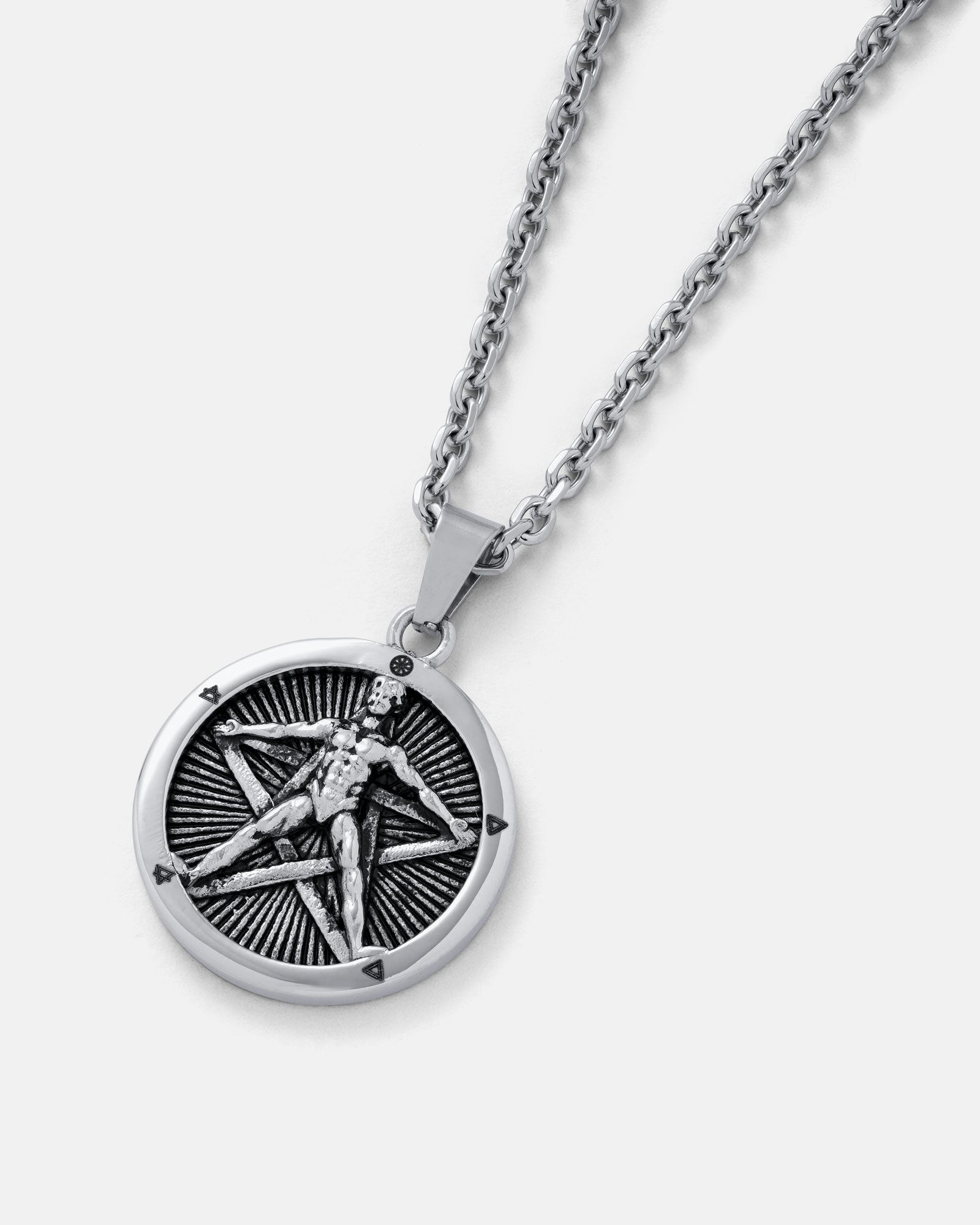 The Star of the Magi" Pendant is a silver stainless steel necklace featuring a round charm with a raised human figure inside a five-pointed star on a textured background—a striking and unique piece of jewelry.