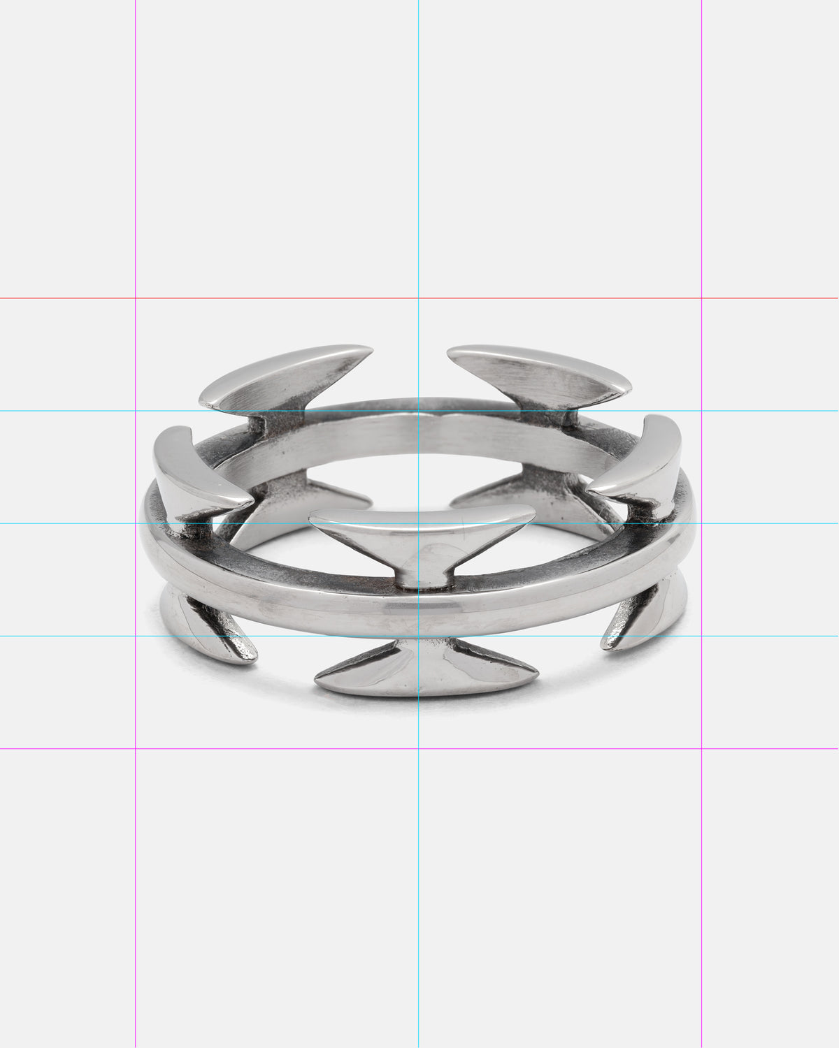 Introducing the Razor Wire Ring by Statement Collective—a stainless steel band ring featuring sharp, arrow-like spikes evenly arranged around its outer rim. Showcased against a white backdrop with subtle blue and pink grid lines, this bold streetwear accessory captures the edgy aesthetic of razor wire-inspired jewelry.