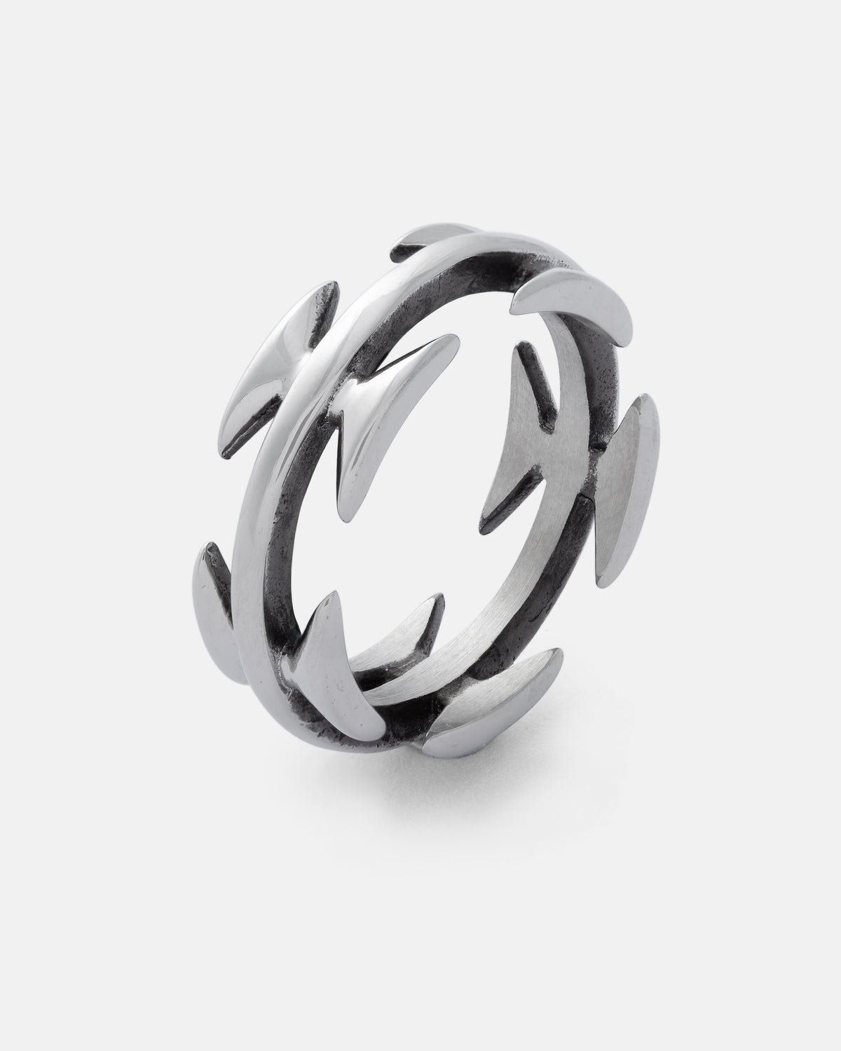 Introducing the Razor Wire Ring by Statement Collective—a striking piece of streetwear jewelry crafted in silver. This ring features evenly spaced, curved, thorn-like spikes that extend outward from both the inner and outer edges, creating a bold and edgy look that commands attention. Displayed against a plain white background.