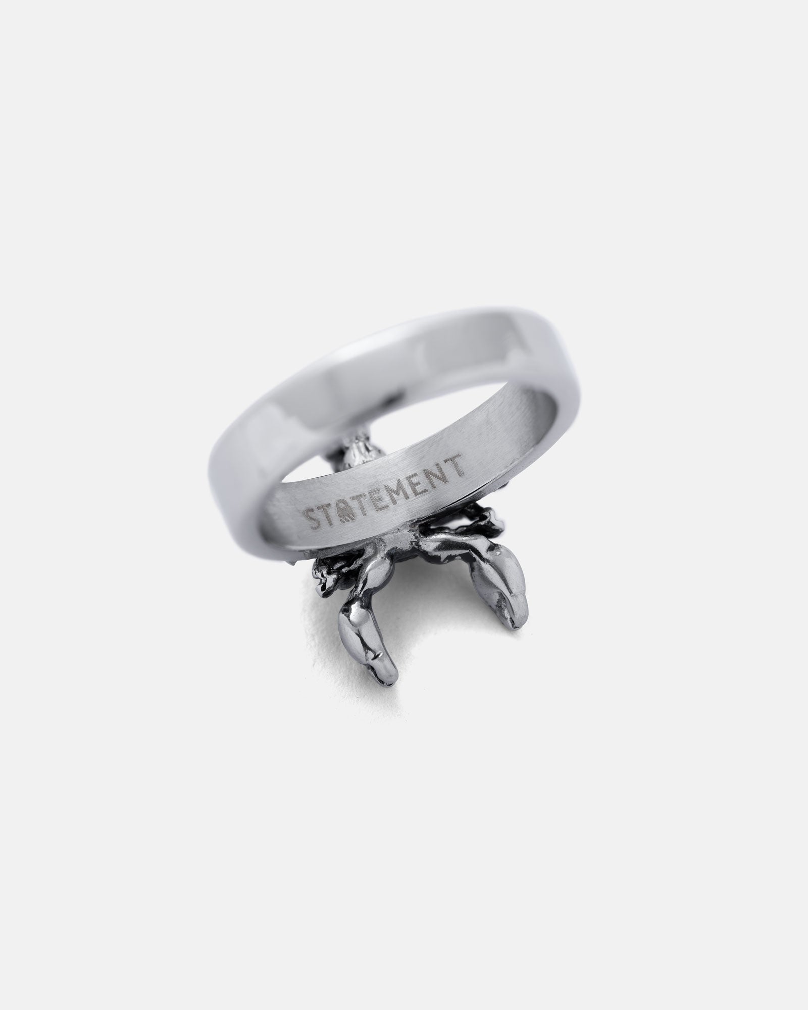 Silver scorpion ring with 'STATEMENT' engraving on a white background