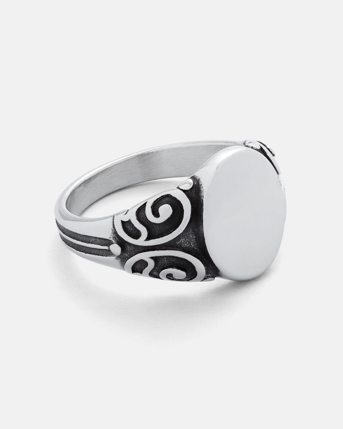 The Statement Collective Mini Oval Scroll Signet Ring features a silver, oval-shaped face and decorative black traditional scroll pattern swirl designs on the band, showcased against a white background.