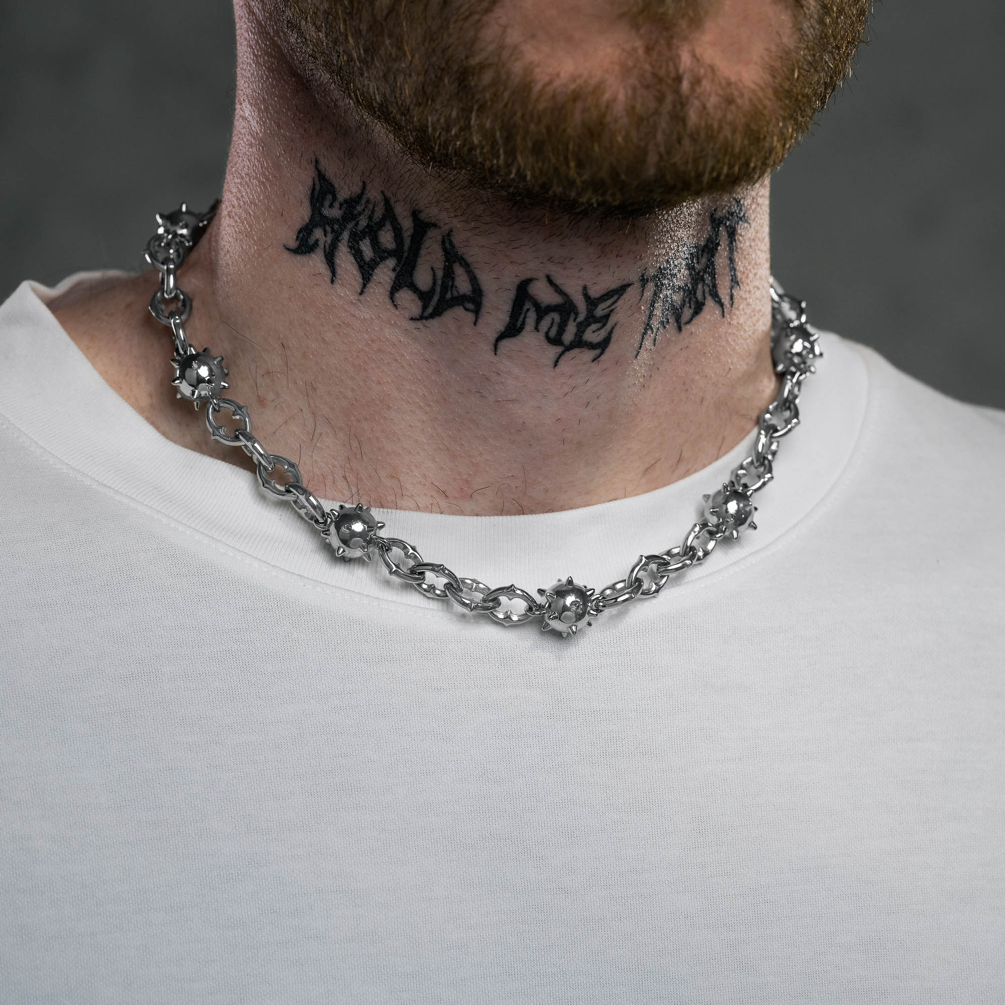 Silver spiked chain with spiked balls every 4 links on male model with neck tattoo