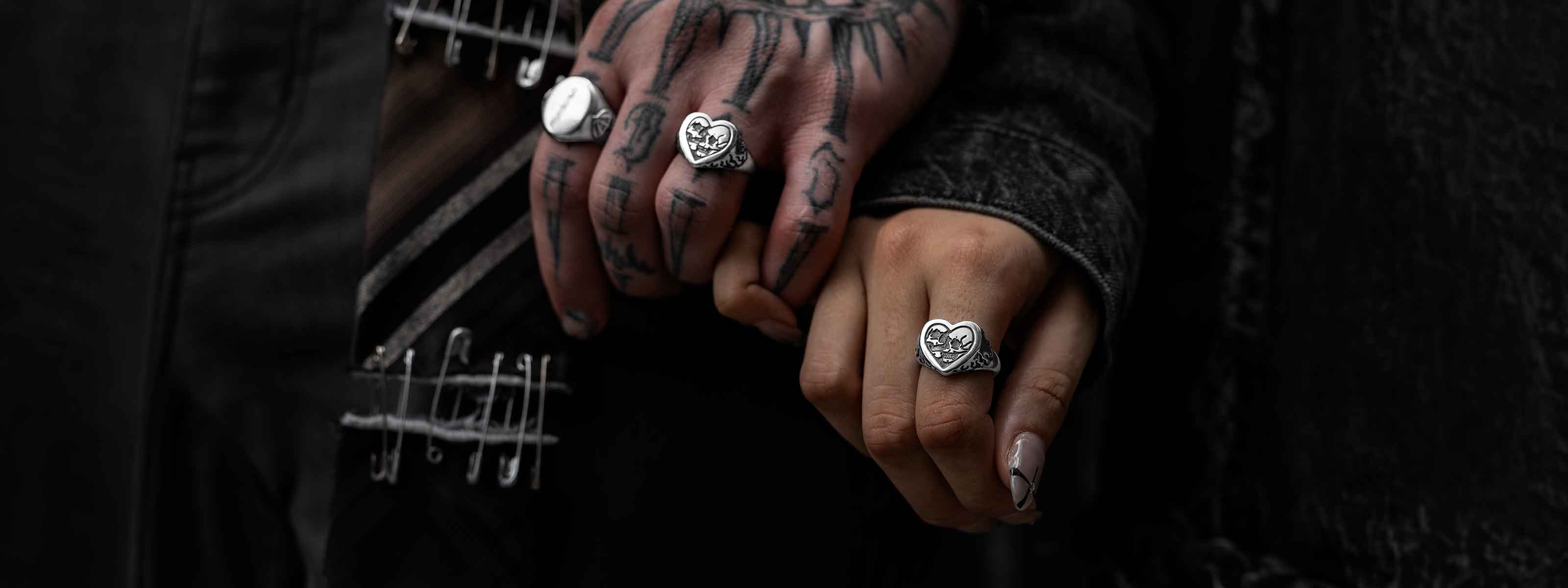 male and female hands with pinky fingers interlocked showing the skull heart rings on both hands.